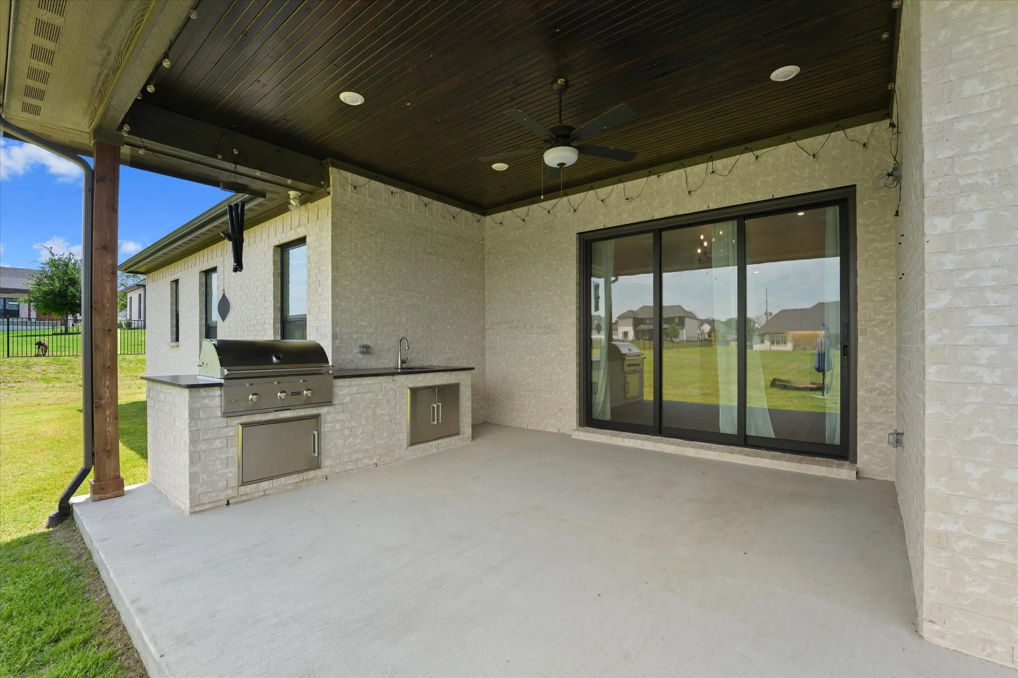 Covered patio featuring an outdoor kitchen with a built-in grill, sink, and stainless steel cabinetry