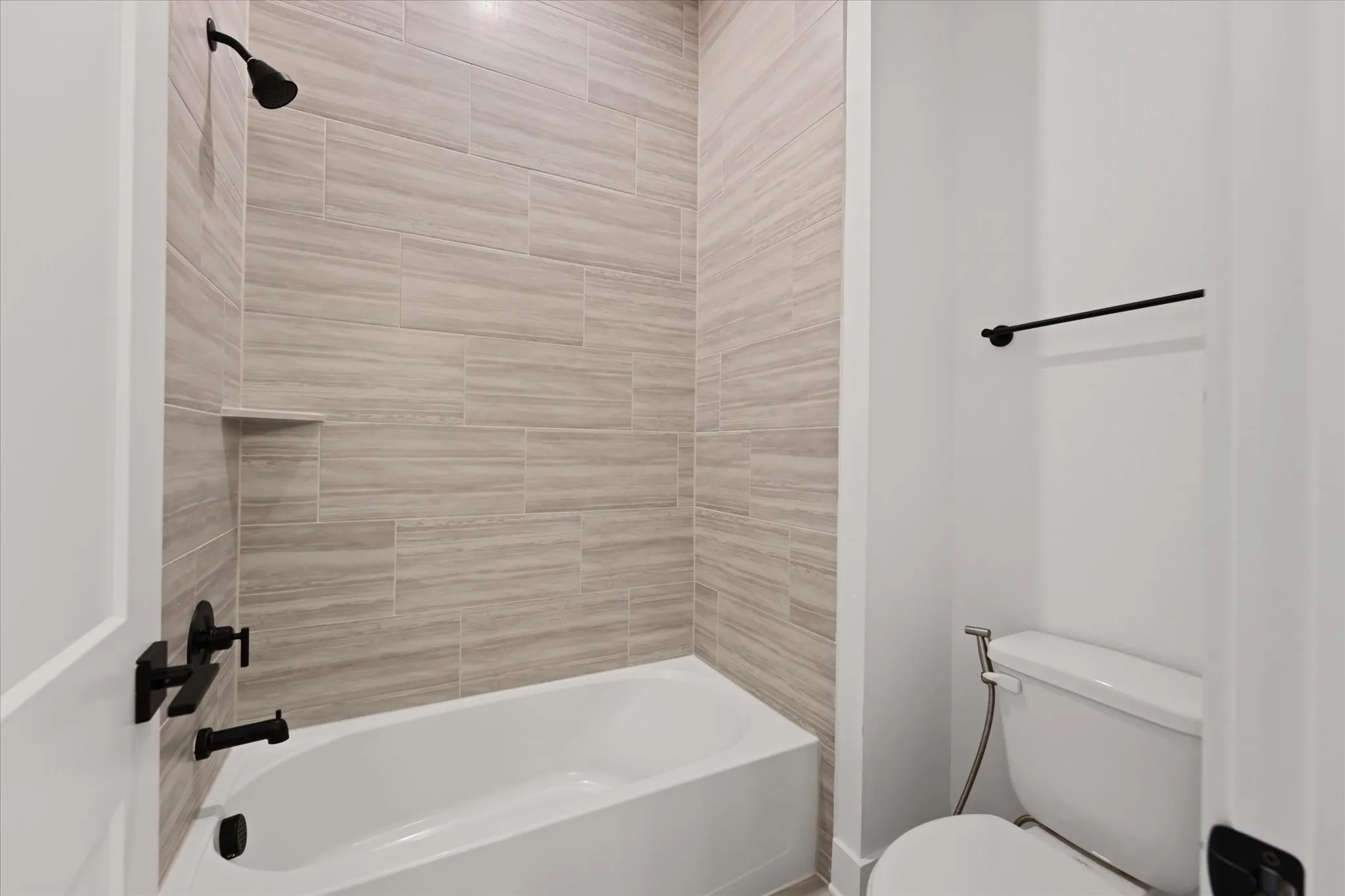 Bathtub with light-toned tiled surround and integrated niche