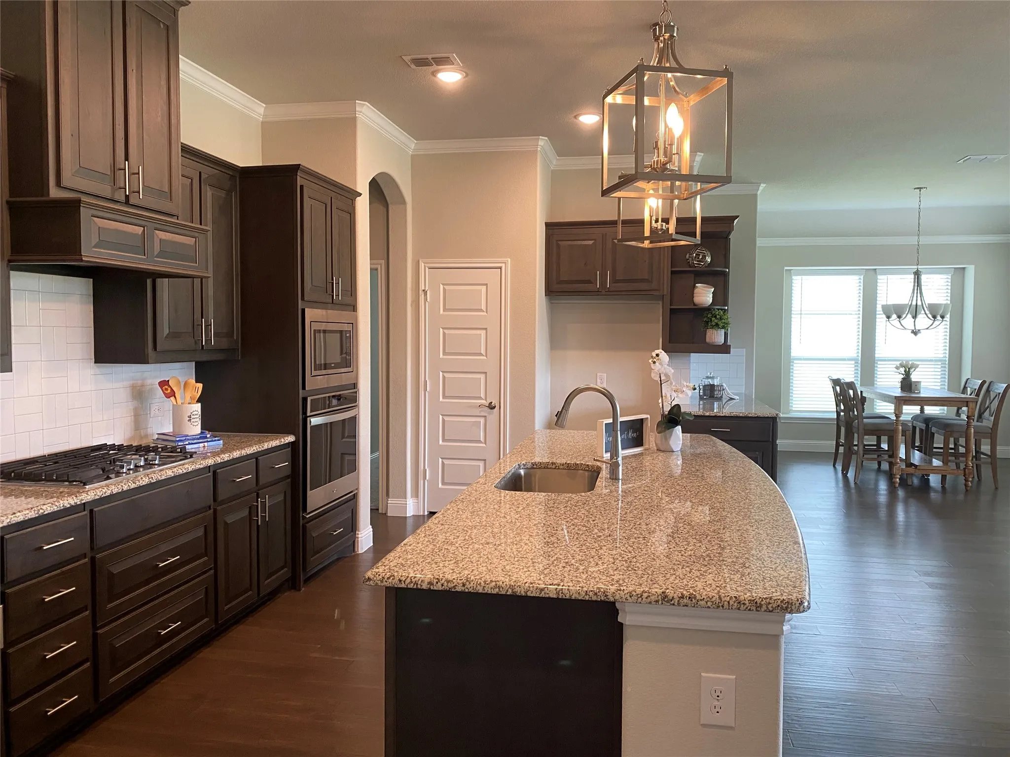 Kitchen featuring sink, tasteful backsplash, stainless steel appliances, dark hardwood / wood-style floors, and an island with sink