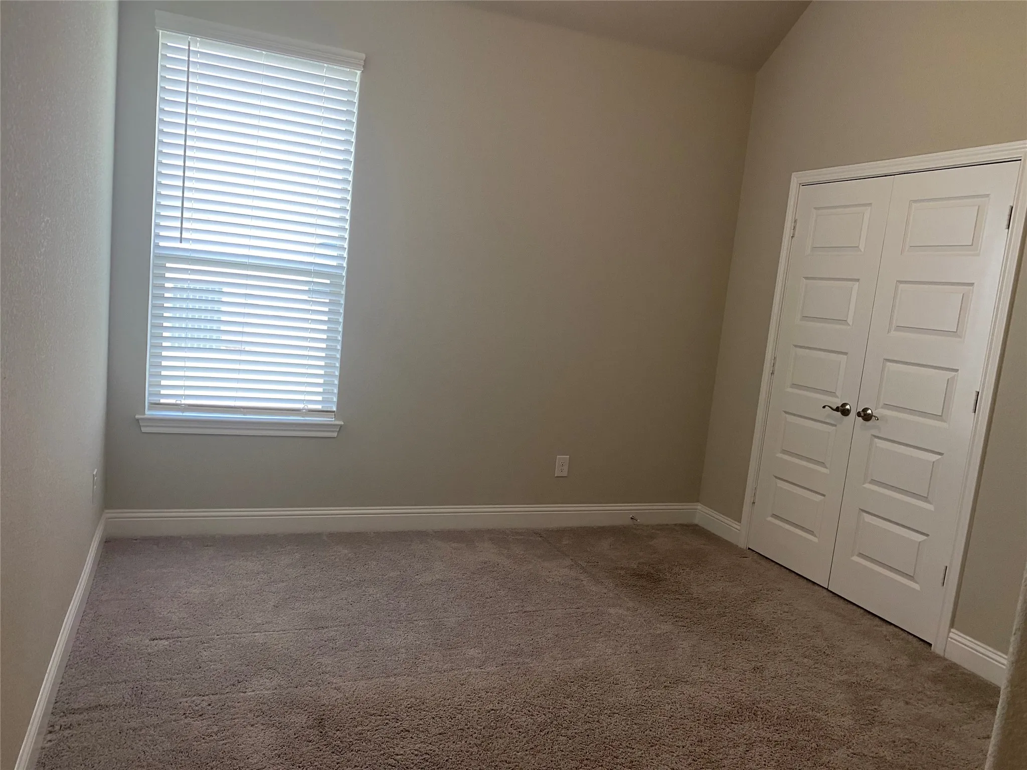 Empty room featuring vaulted ceiling and carpet flooring