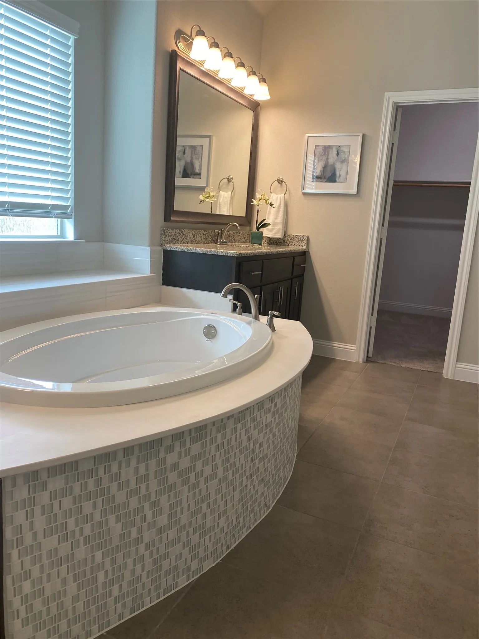Bathroom featuring tiled tub, tile flooring, and vanity