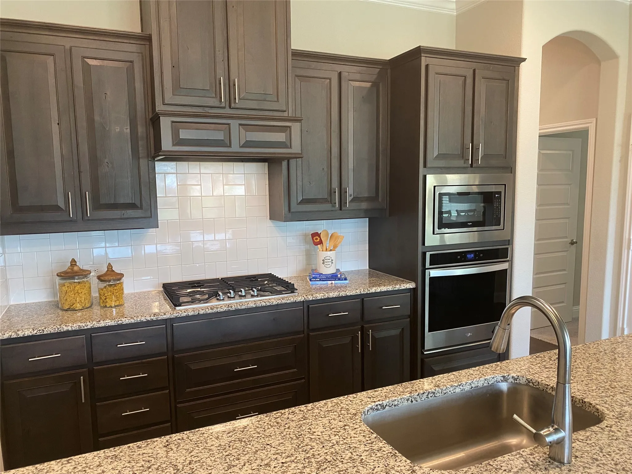 Kitchen with sink, tasteful backsplash, stainless steel appliances, and light stone counters