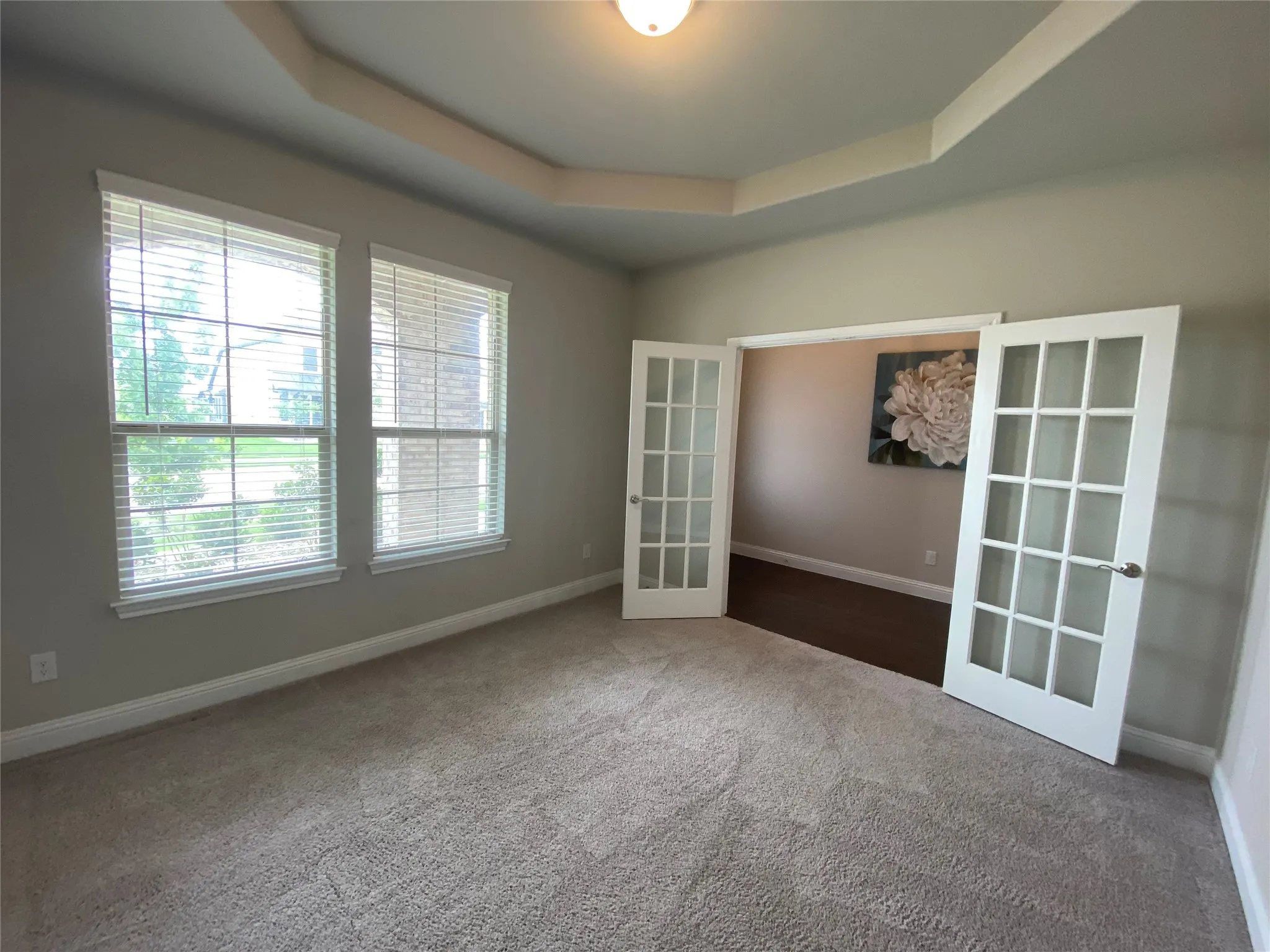 Unfurnished room featuring french doors, dark colored carpet, and a tray ceiling