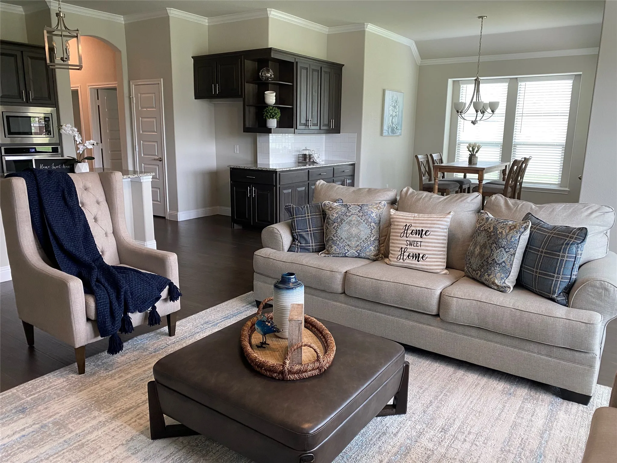 Living room with wood-type flooring, a notable chandelier, and ornamental molding