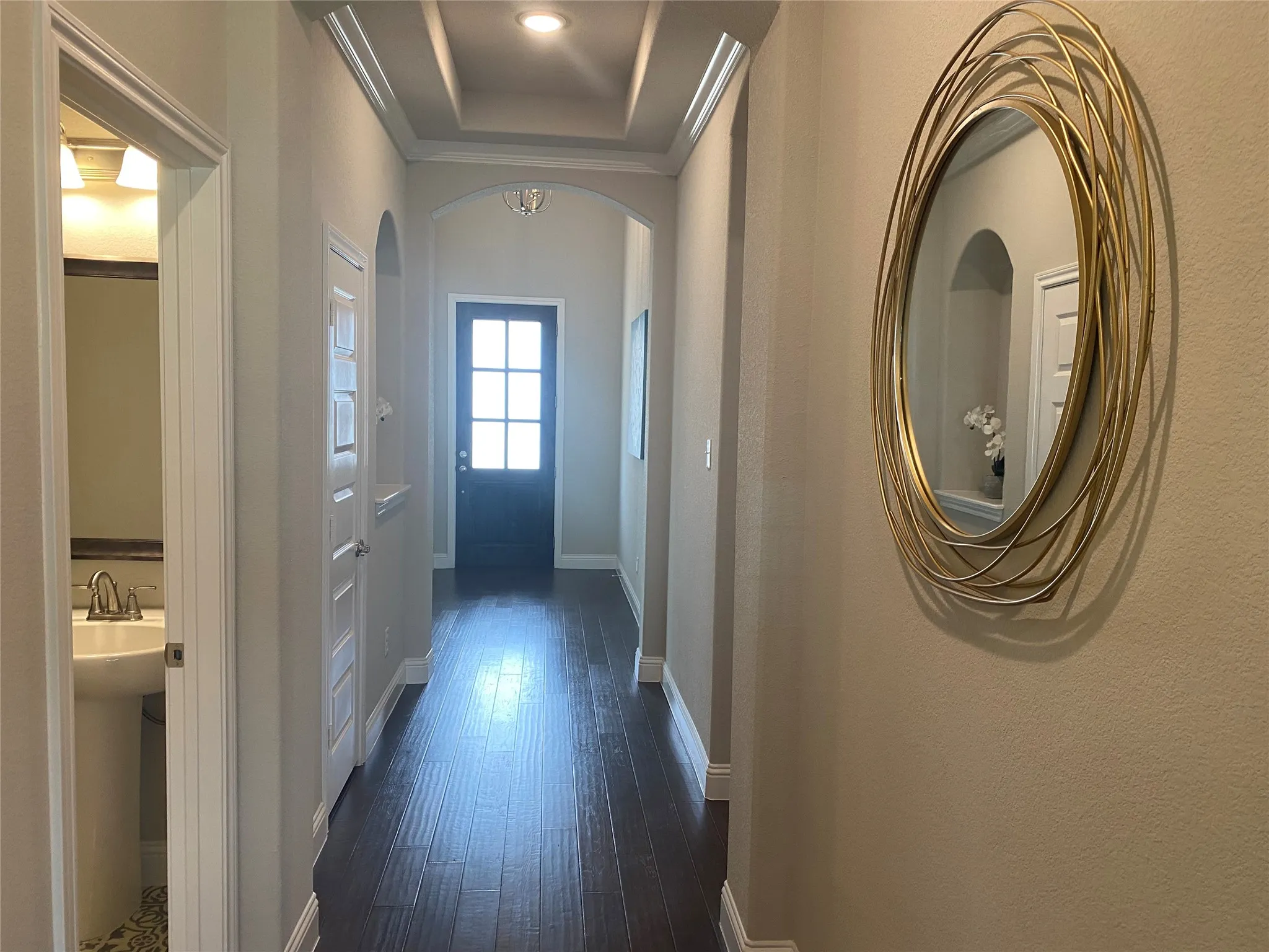 Corridor featuring ornamental molding, a tray ceiling, and dark wood-type flooring