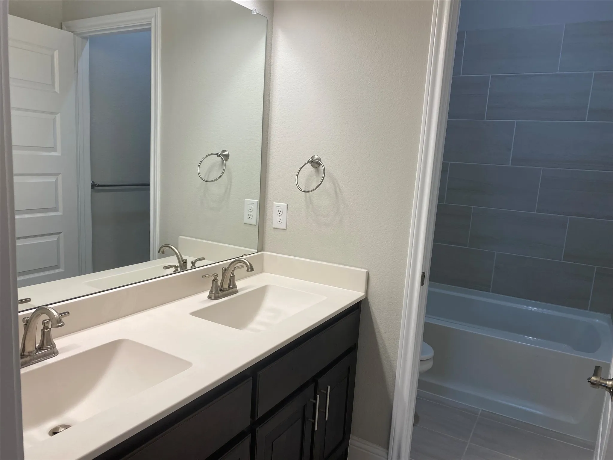 Full bathroom with toilet, double vanity,  shower combination, and tile flooring