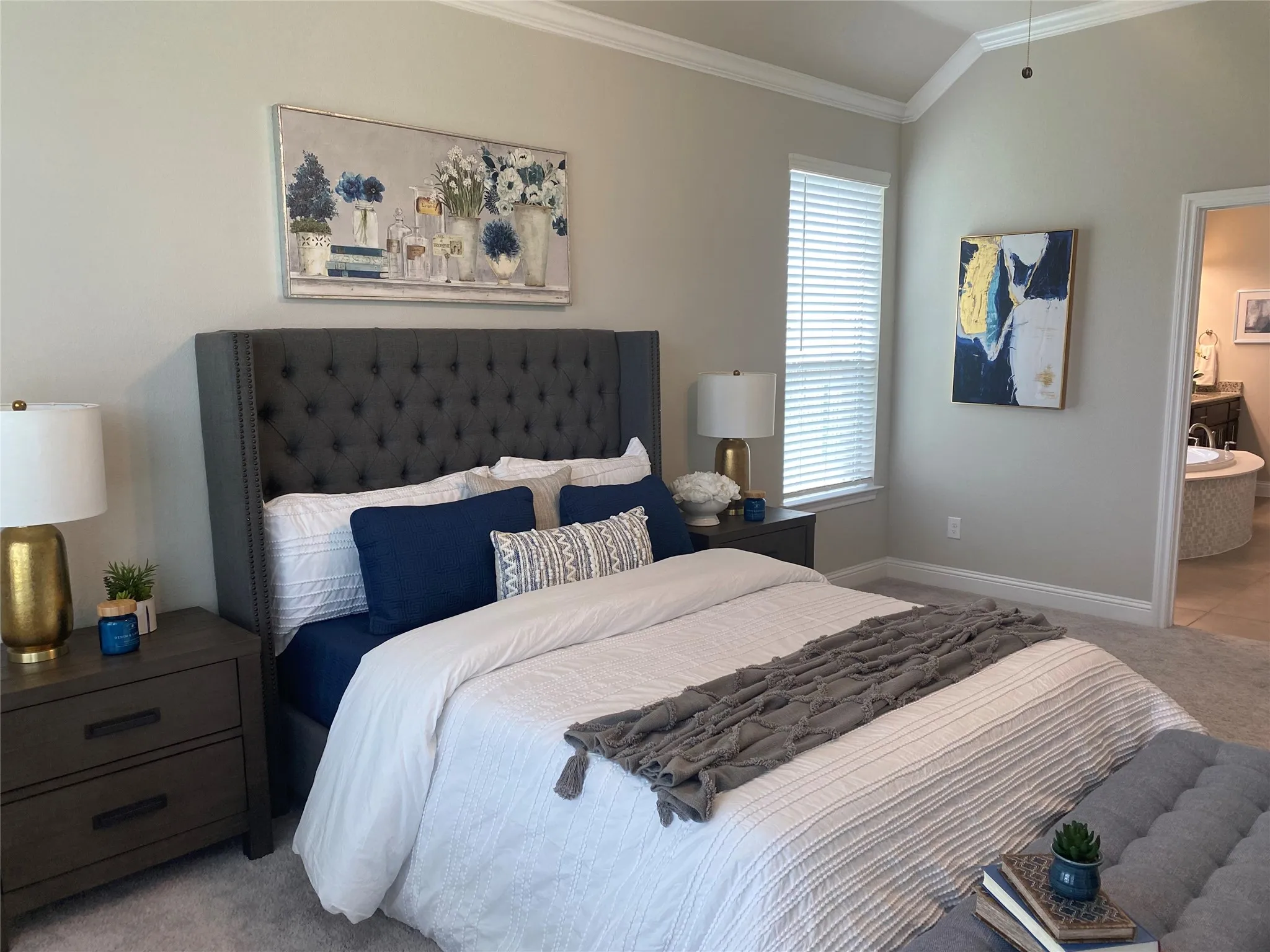 Carpeted bedroom featuring vaulted ceiling, ensuite bathroom, and ornamental molding
