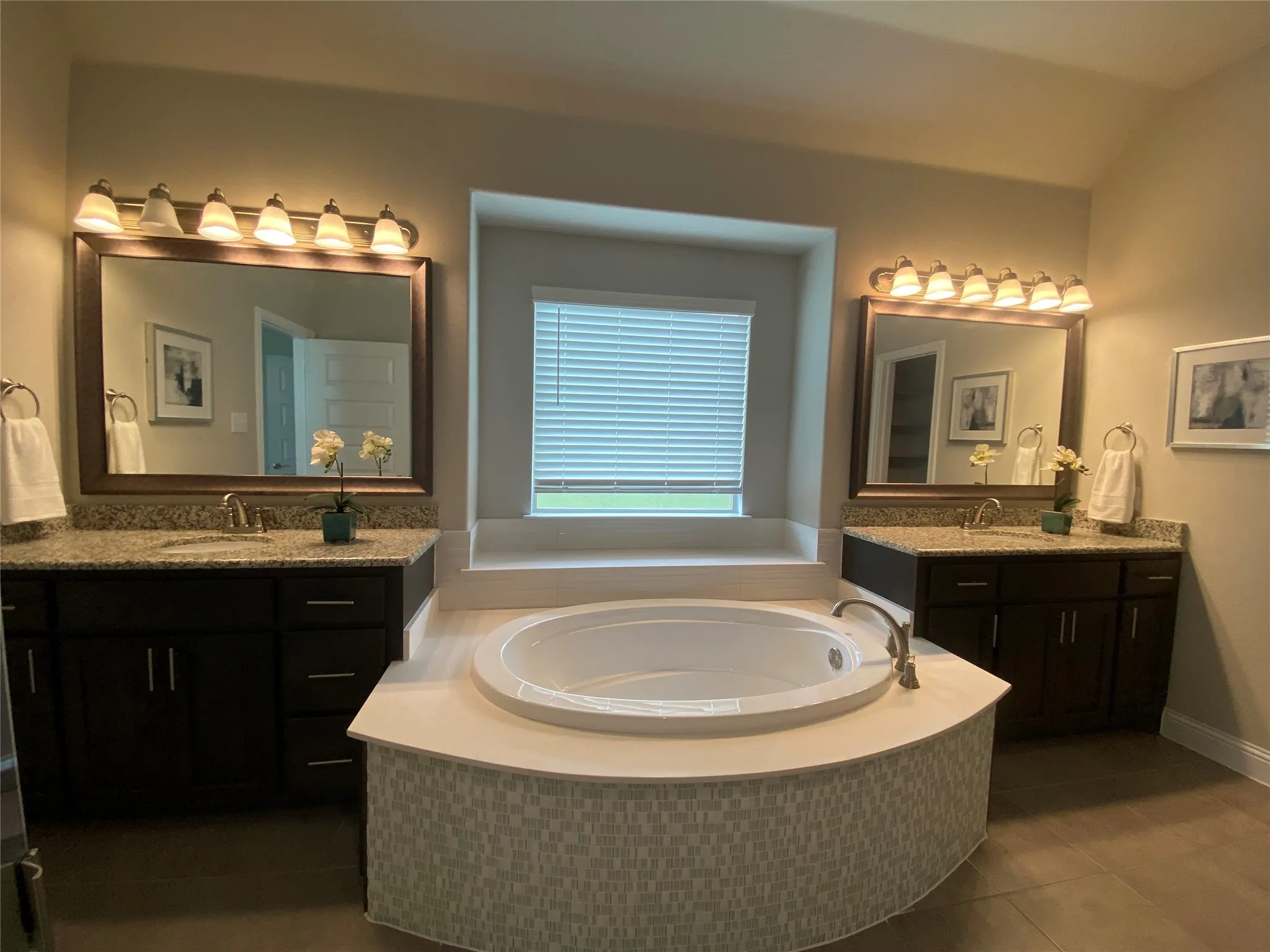 Bathroom with tile floors, tiled tub, dual vanity, and vaulted ceiling