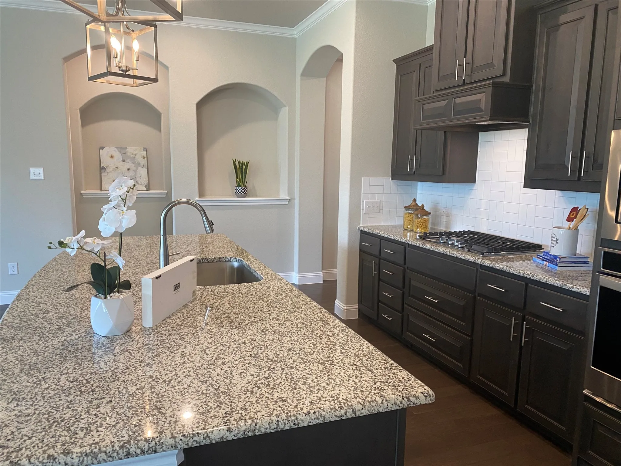 Kitchen featuring dark hardwood / wood-style flooring, tasteful backsplash, a kitchen island with sink, and stainless steel gas stovetop