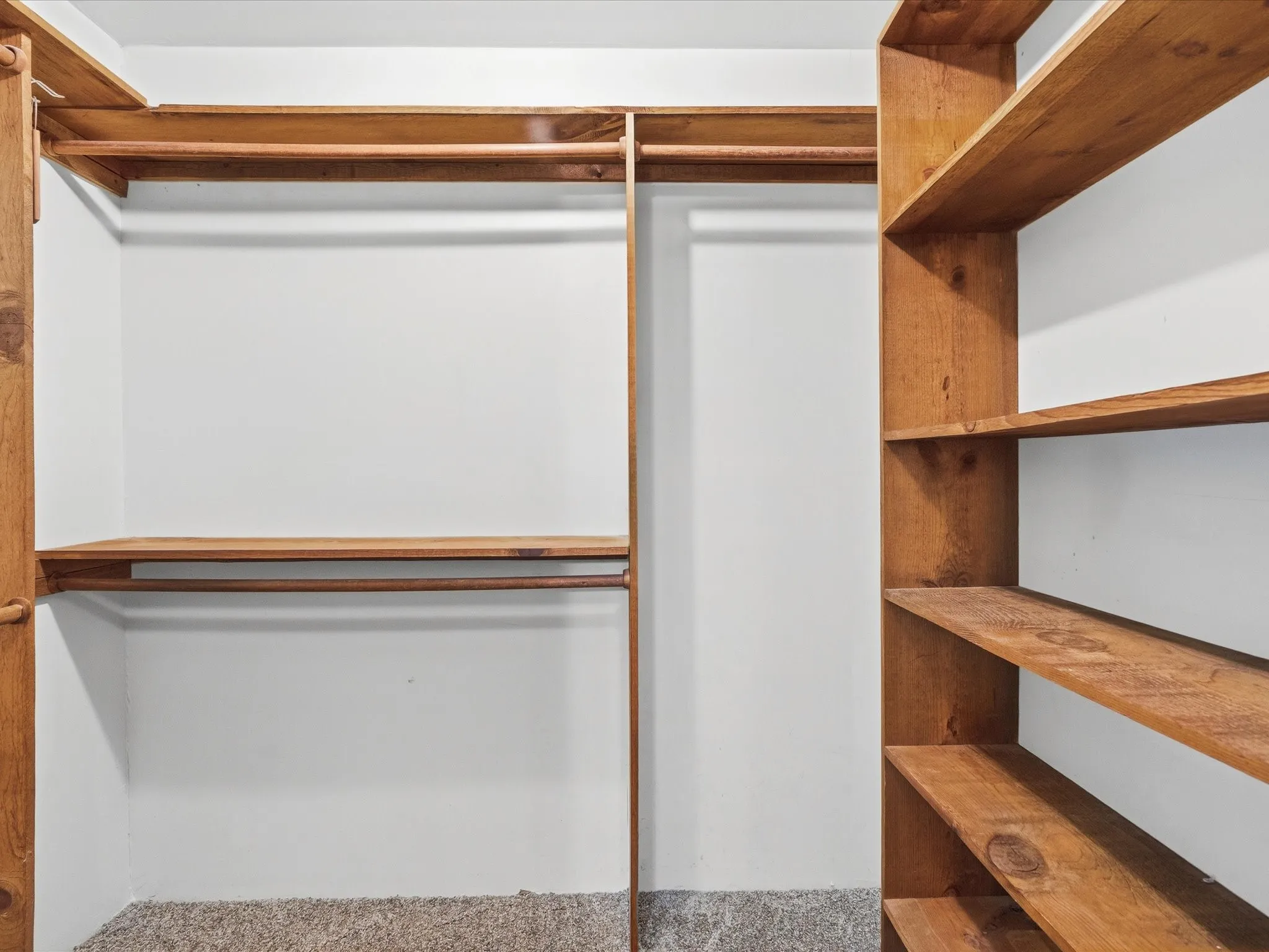 Primary closet system featuring natural wood-finish shelving and hanging rods