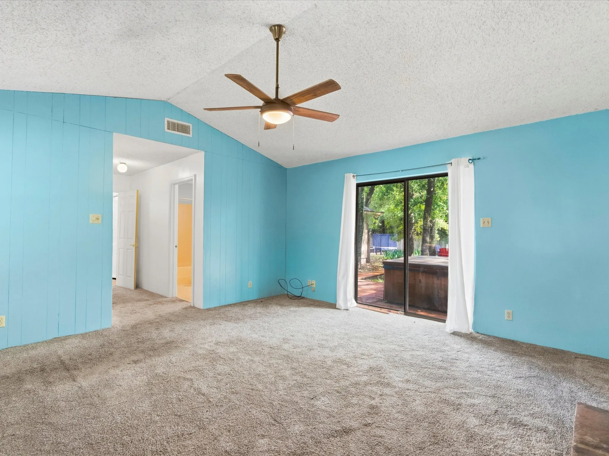 Spacious room featuring vaulted ceilings, a ceiling fan with integrated lighting, and carpet flooring