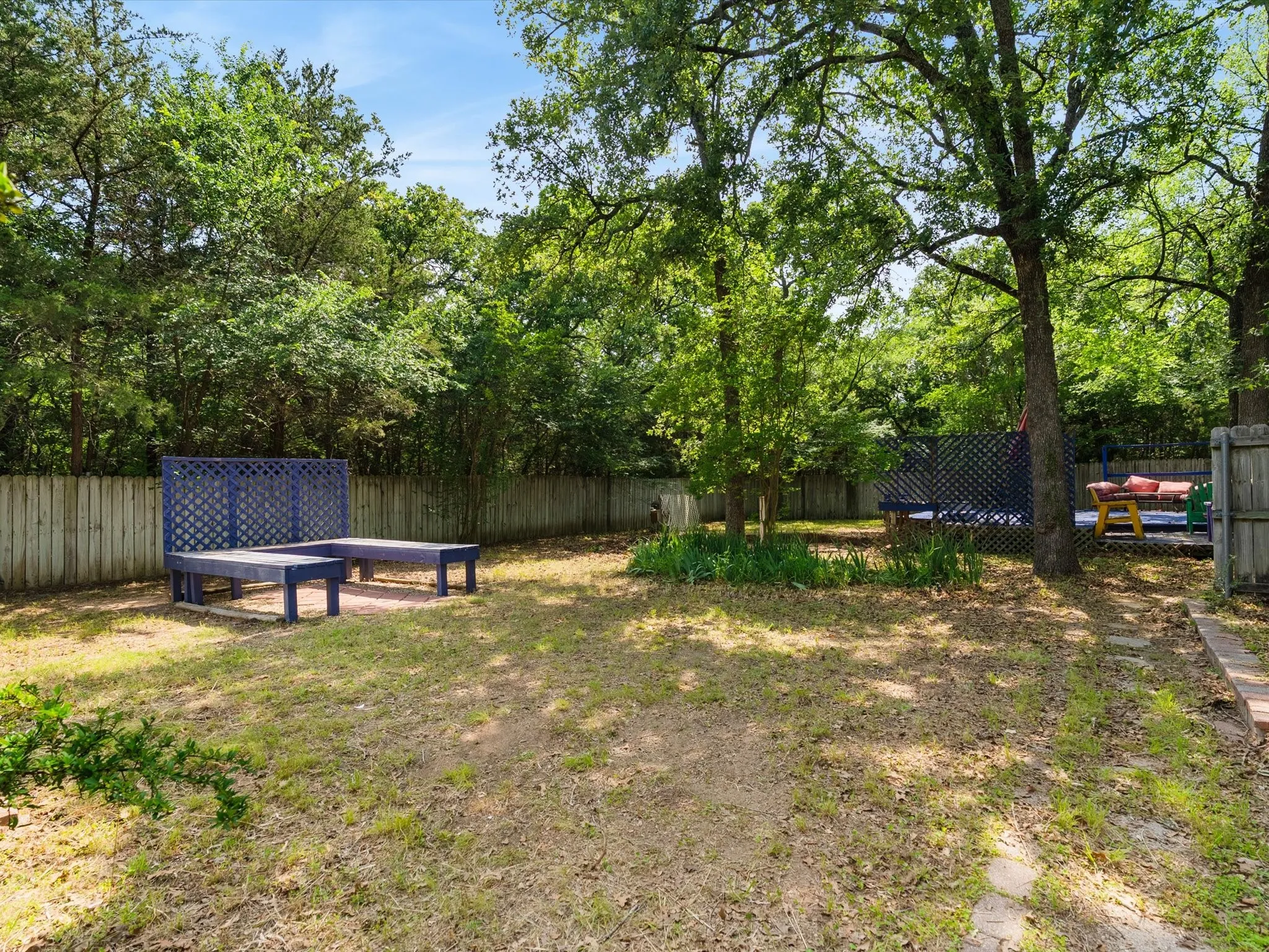 Large fenced in backyard area featuring mature trees