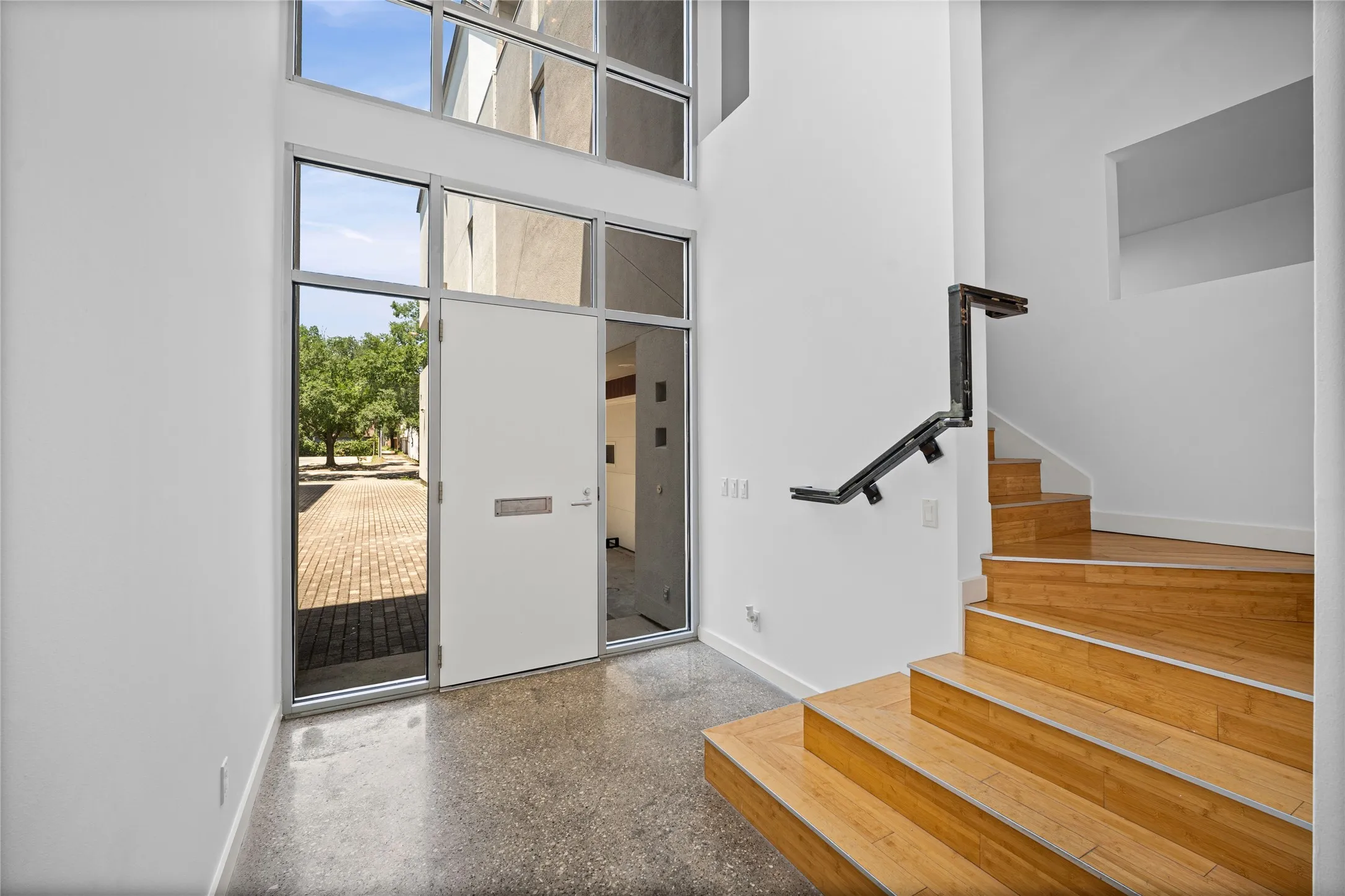 Two-story entry with full-light exterior door, transom windows, and polished concrete flooring