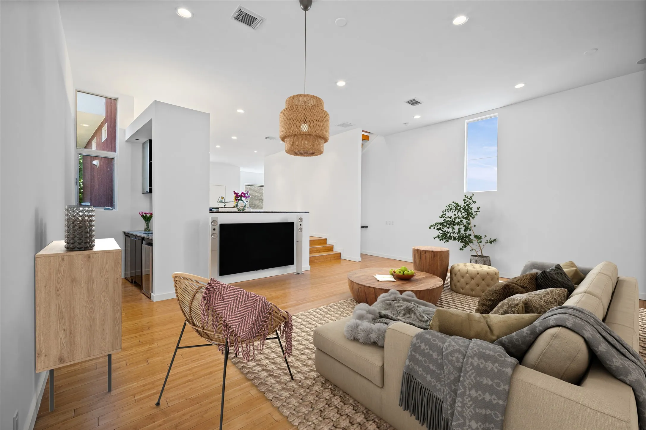 VIRTUALLY STAGED! Open-concept living space featuring wood-finish flooring, recessed lighting, and a woven pendant light fixture