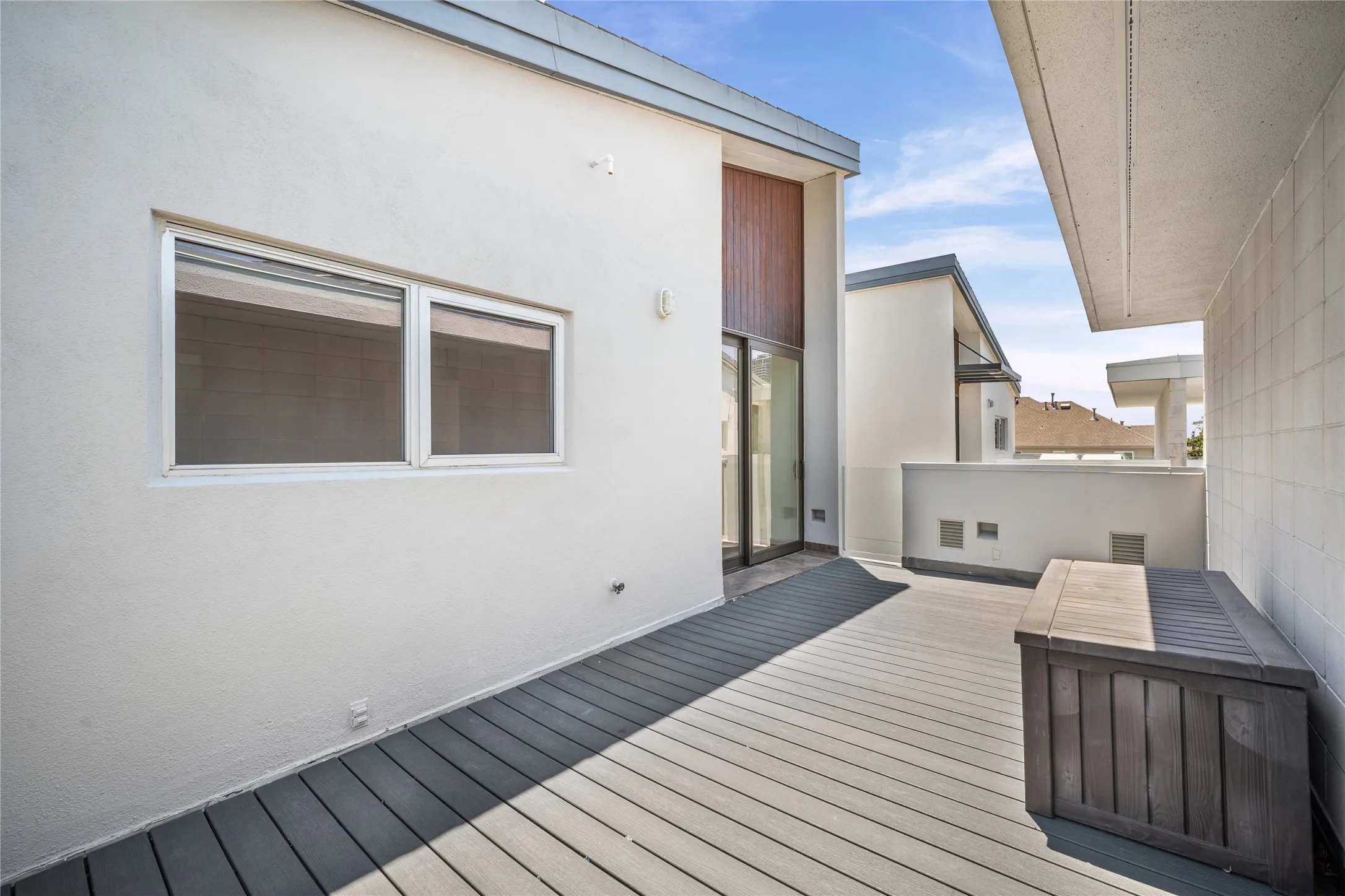 Exterior deck with composite decking, stucco siding, and a sliding glass door