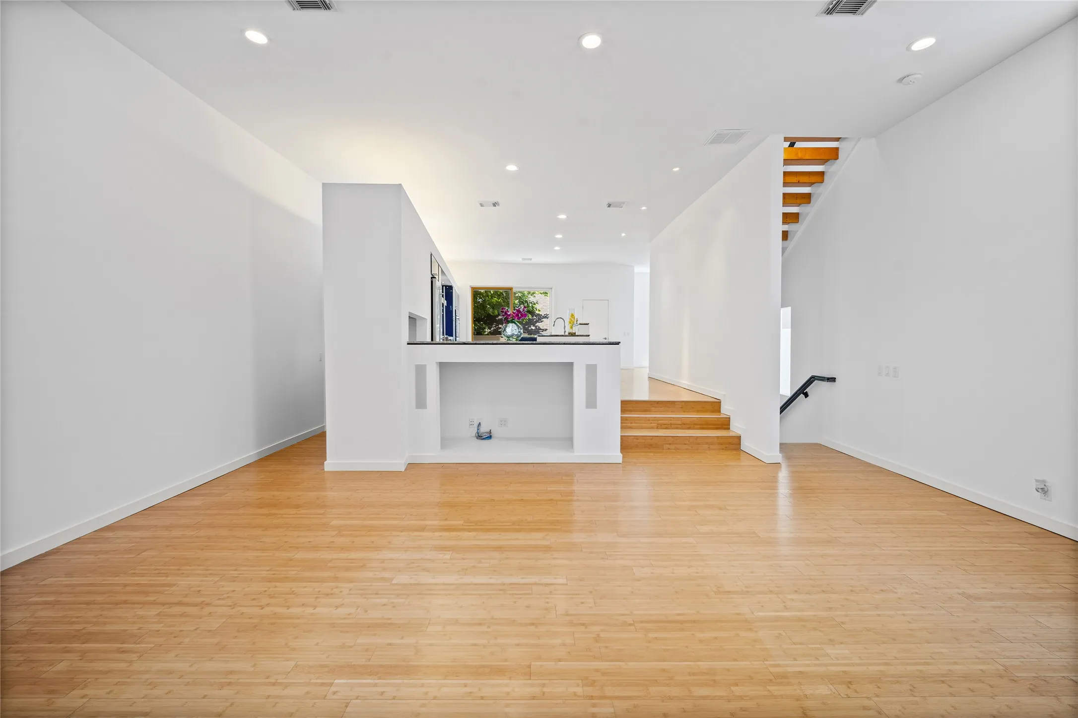 Spacious main living area featuring light wood-finish flooring, white walls, and recessed lighting
