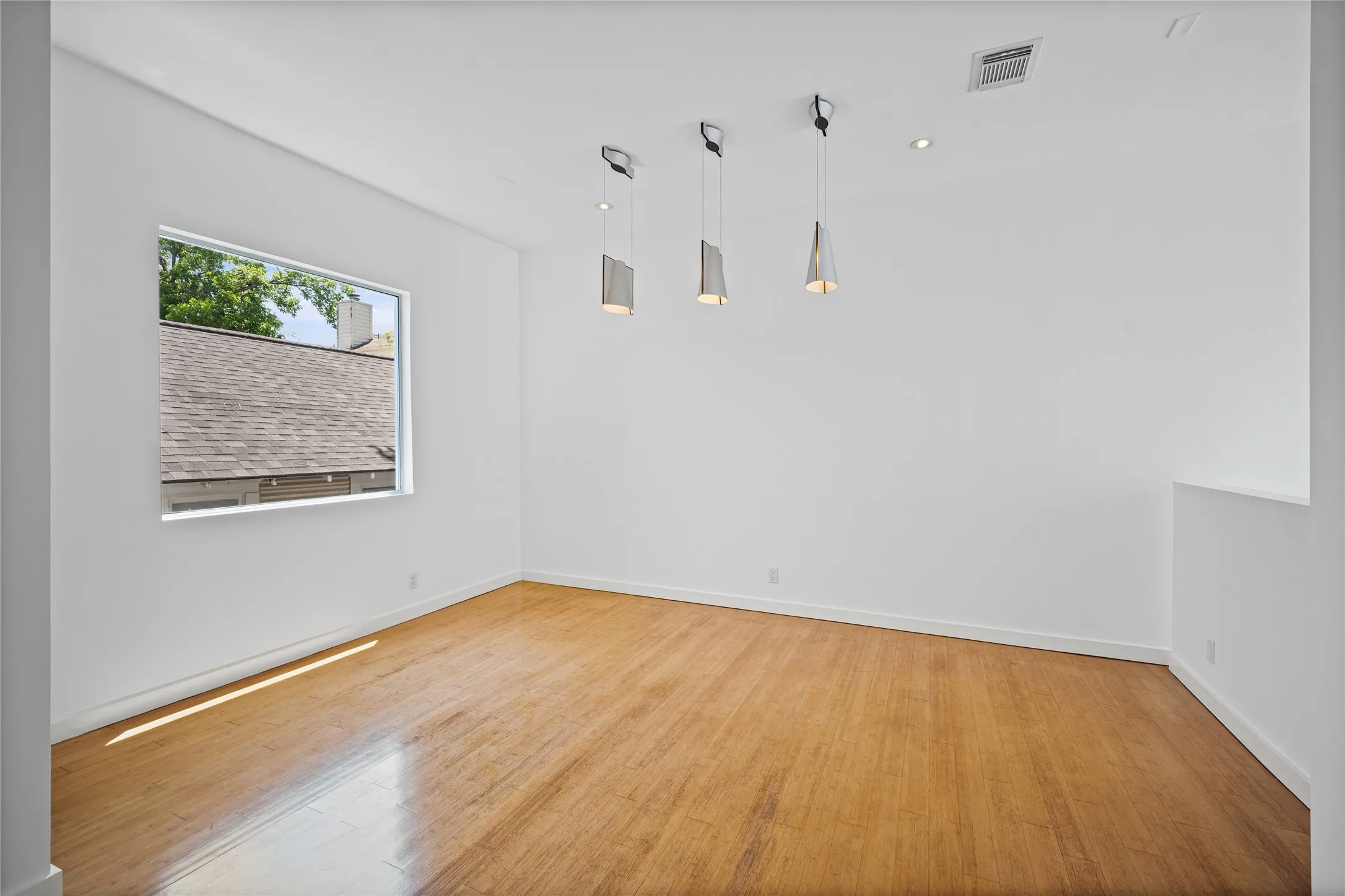 Bright interior space featuring wood-finish flooring, white walls, and a large horizontal window
