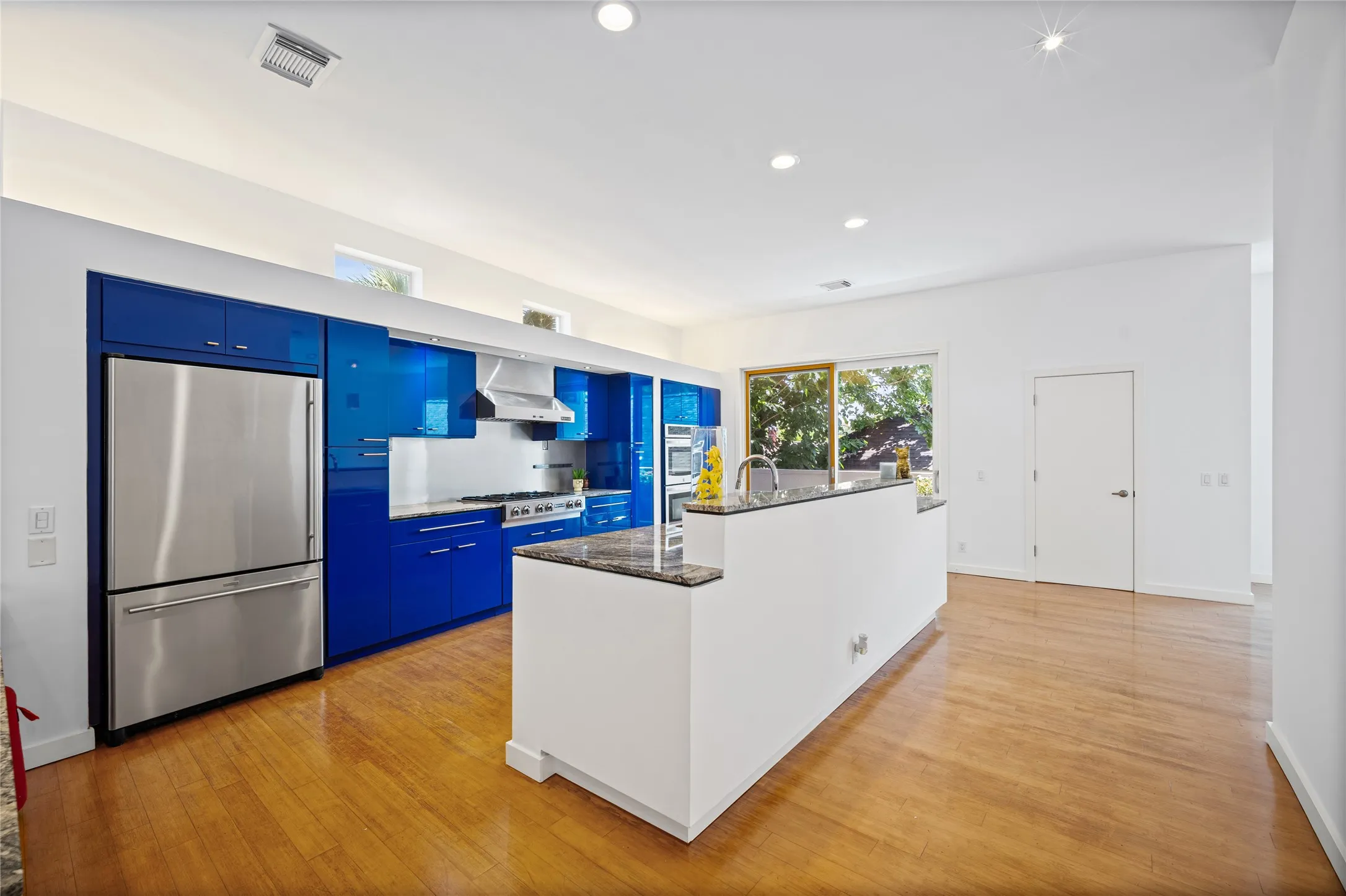 Modern kitchen featuring vibrant blue cabinetry and stainless steel appliances
