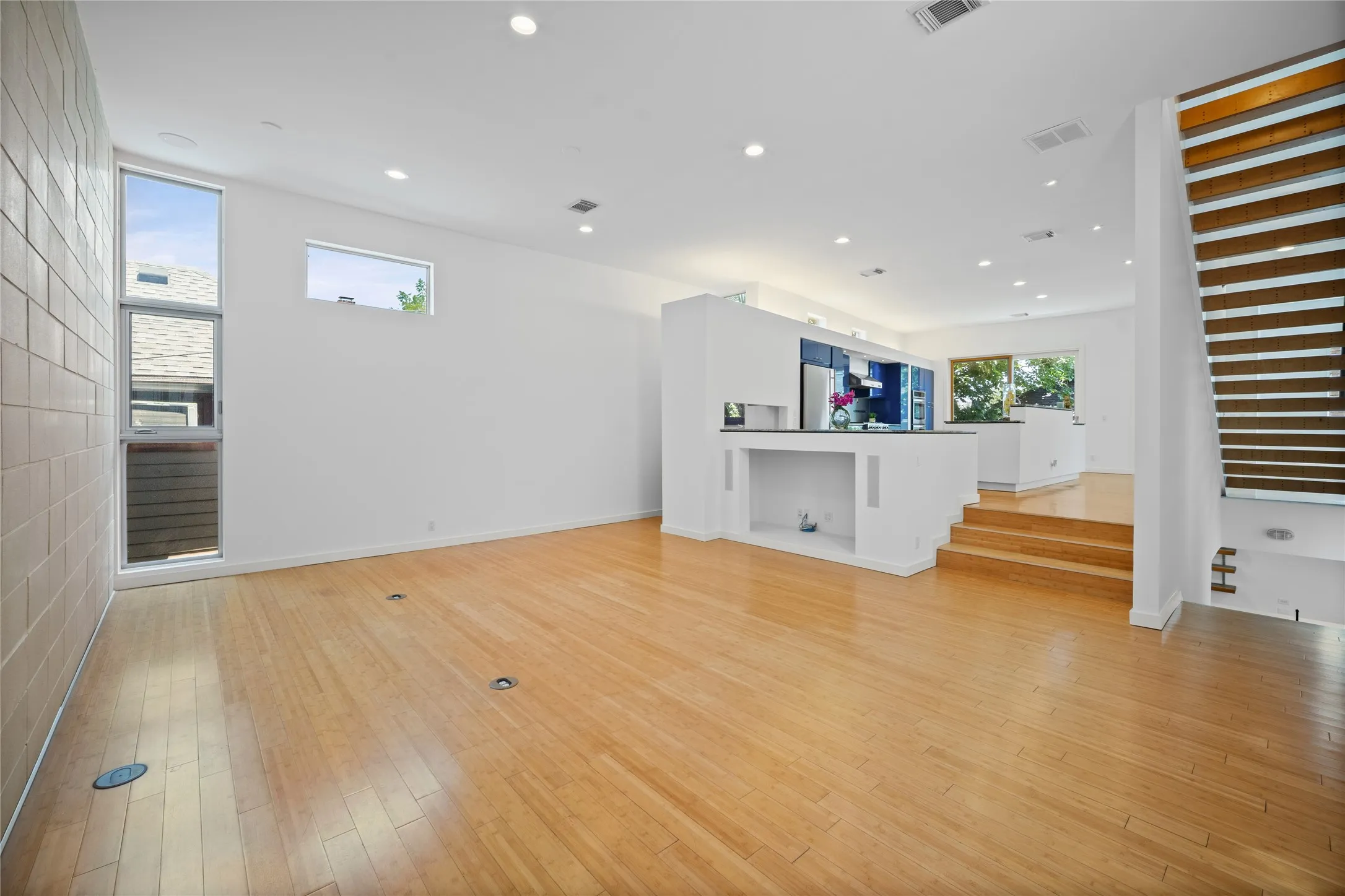 Open-concept living space featuring light wood-finish flooring, recessed lighting, and a modern kitchen with a large island