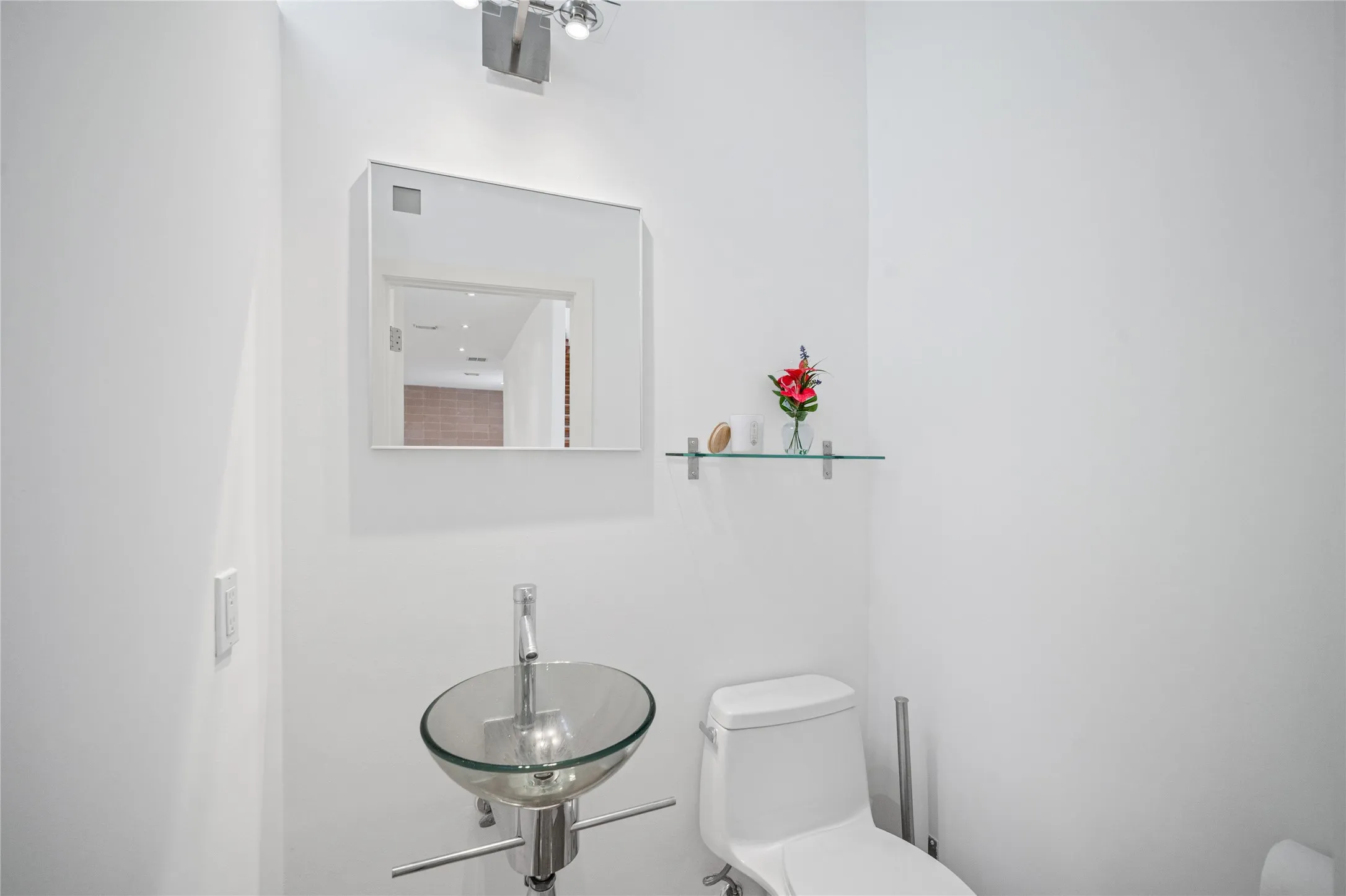 Contemporary powder room featuring a glass vessel sink, wall-mounted faucet, and a sleek mirrored medicine cabinet