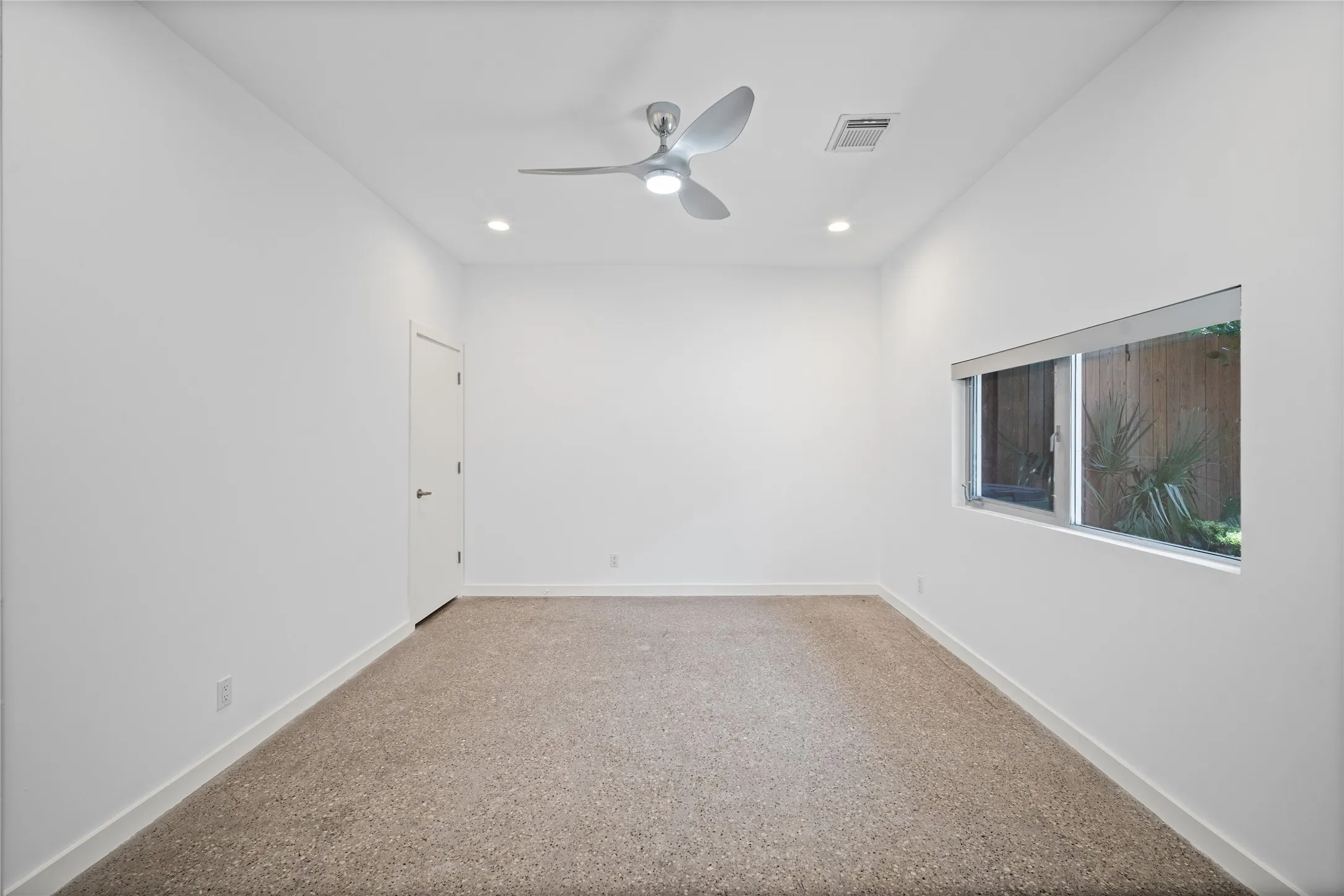 Carpeted room featuring a modern ceiling fan with integrated lighting, recessed lighting, white walls, and a horizontal window providing natural light
