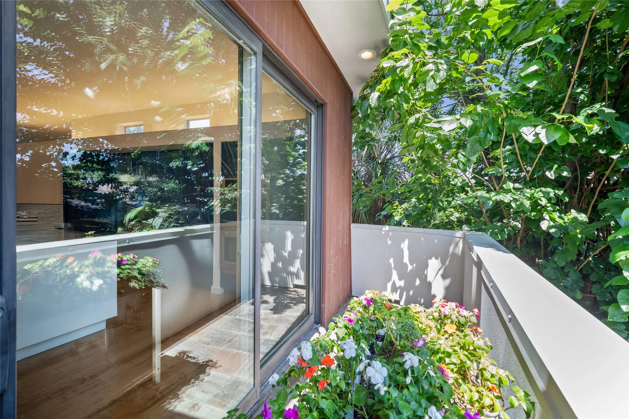 Exterior balcony featuring a metal railing and mature tree canopy