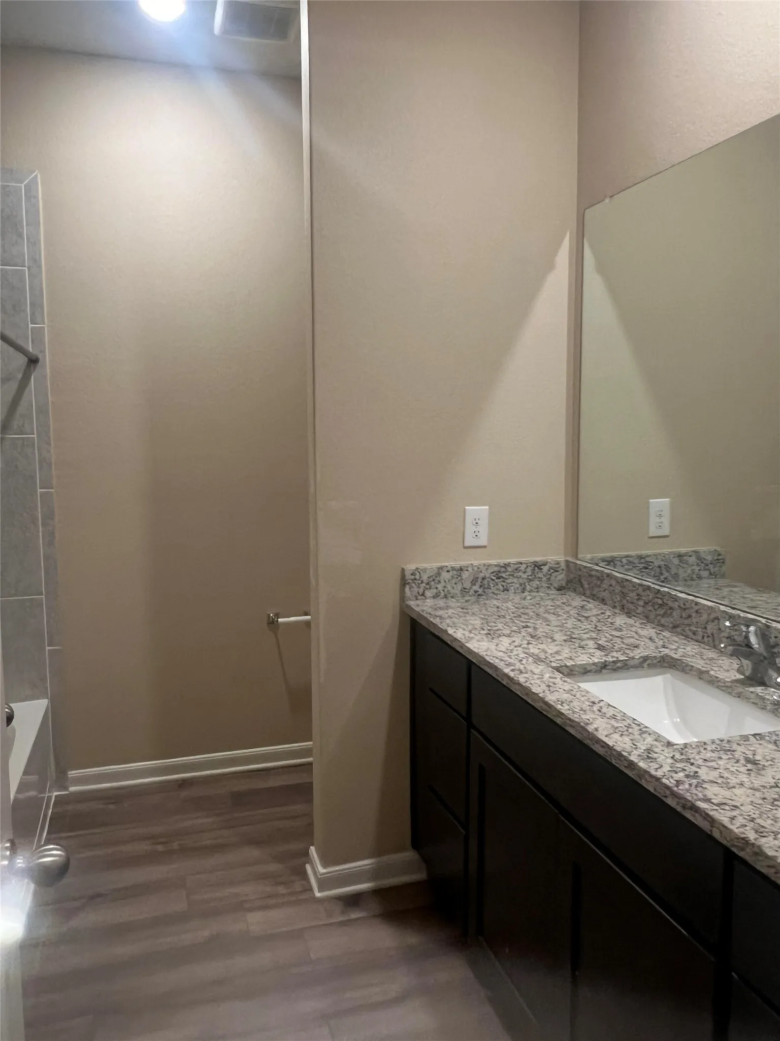Bathroom vanity with a polished granite countertop, integrated rectangular sink, and dark wood-finish cabinetry