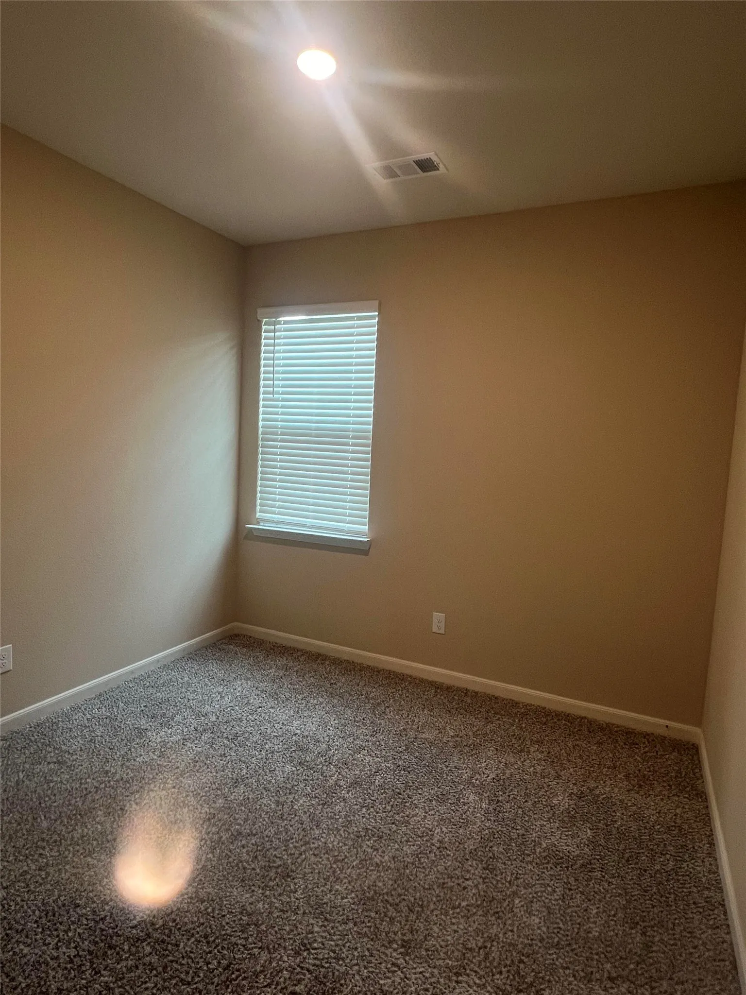 Carpeted interior space featuring a window with horizontal blinds, recessed ceiling lighting, and neutral wall tones