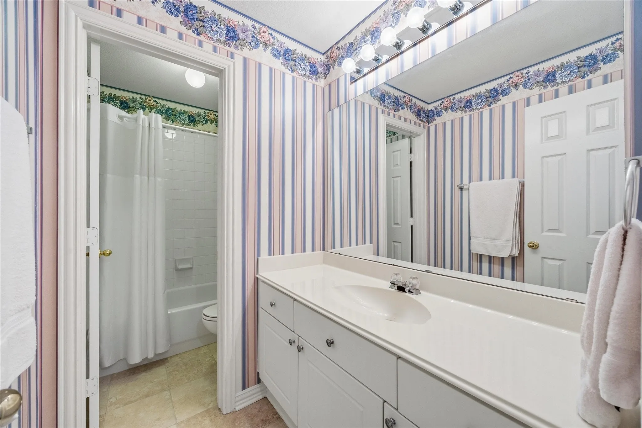 The hall bath is divided into separate areas for the sink-vanity and tub-shower-toilet.