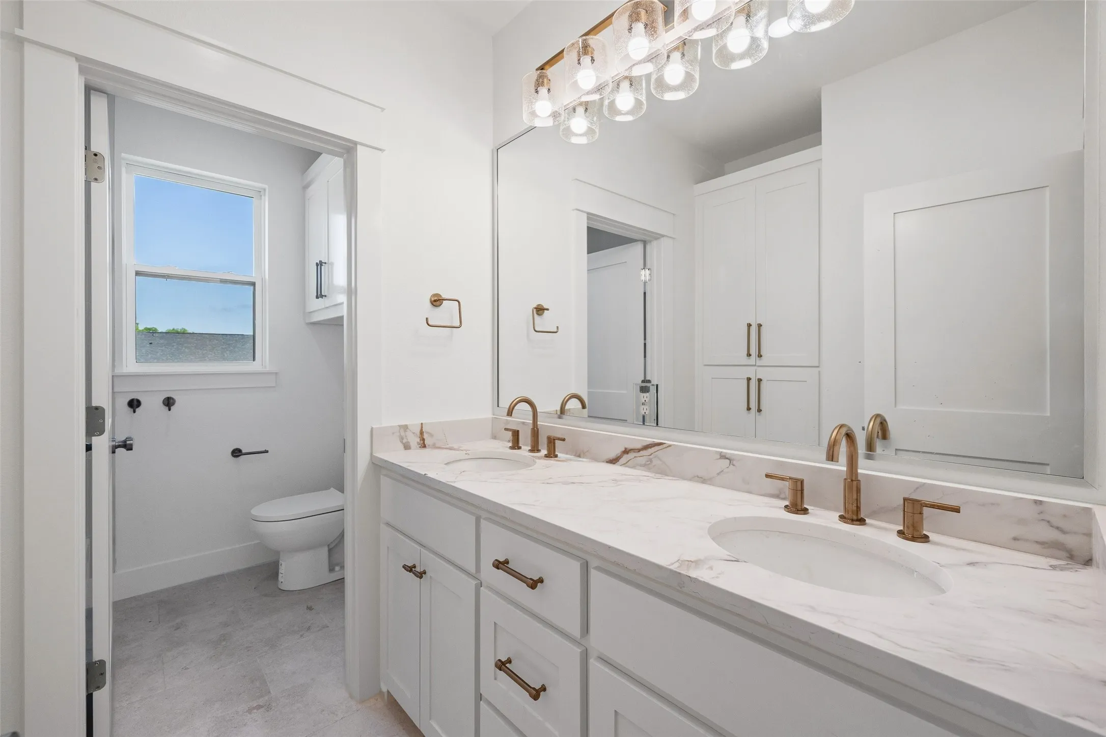 Dual vanity with integrated sinks, marble-finish countertop, and brushed brass fixtures