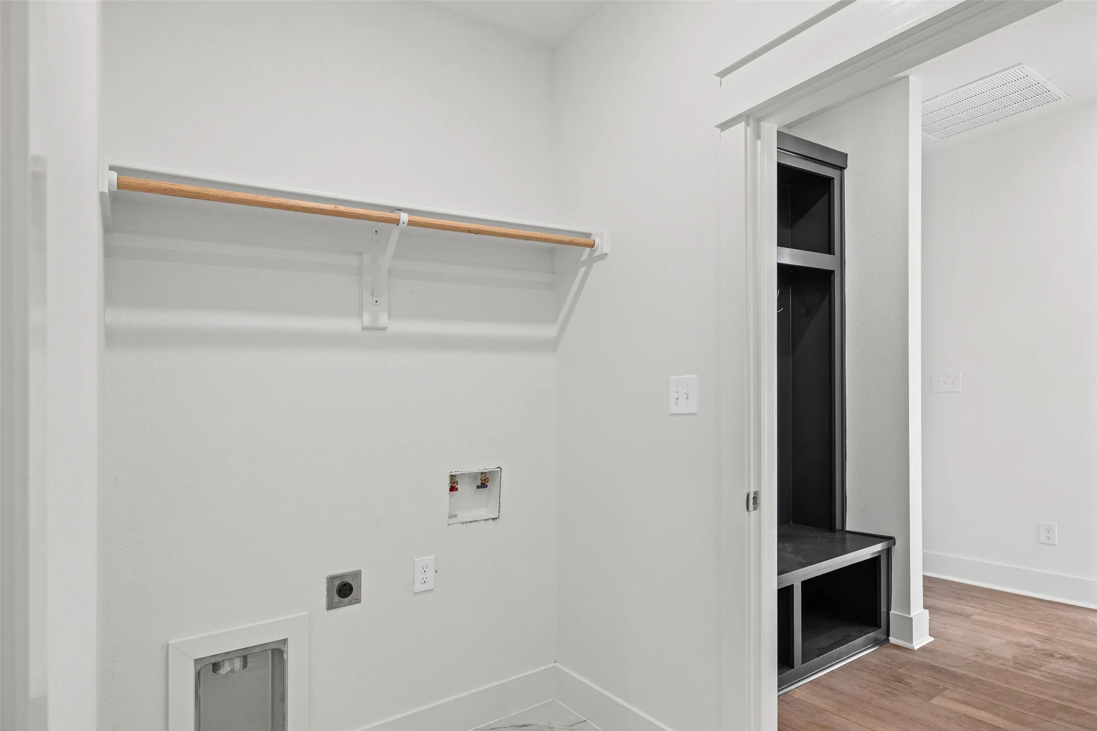 Dedicated laundry area featuring a clothing rod, utility hookups, and a floor vent