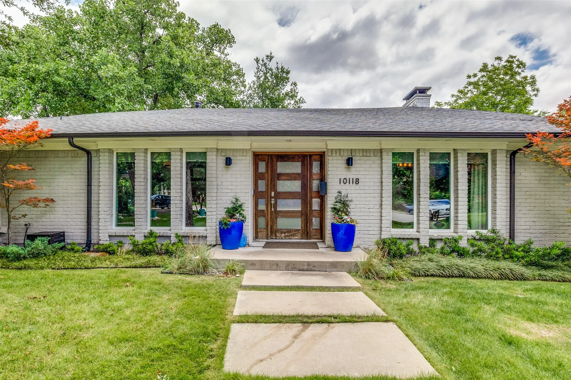 Stunning curb appeal featuring painted brick, mature landscaping, and designer front door.