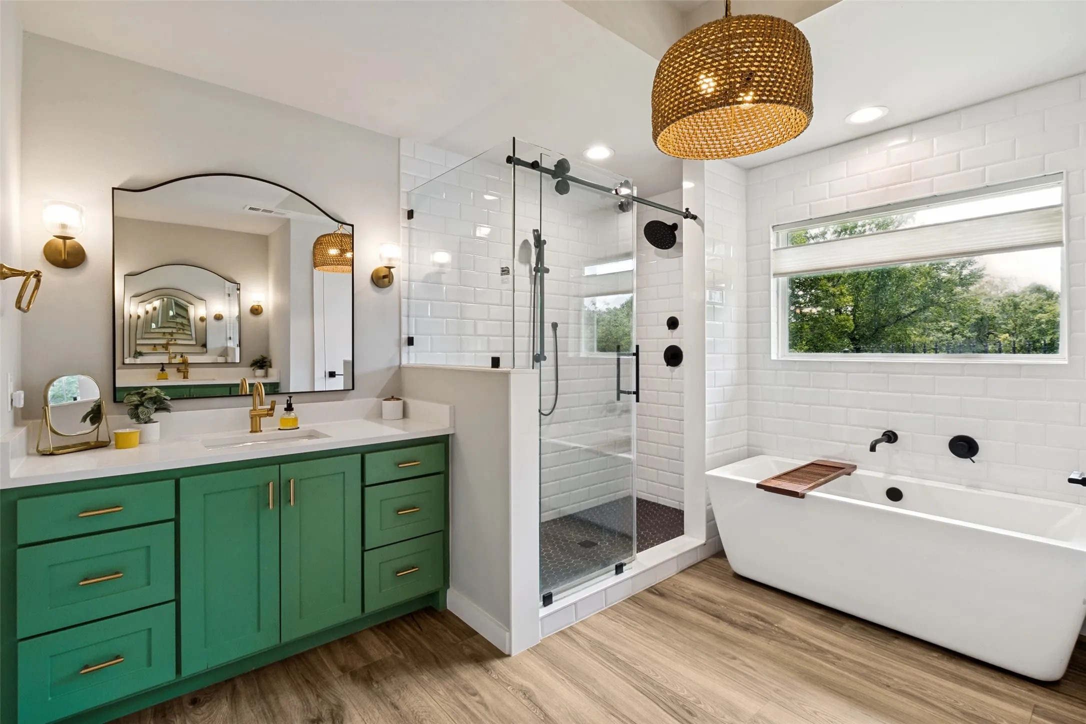 Spa-inspired primary bath features dual emerald green vanities, designer lighting, soaking tub, and striking modern finishes.