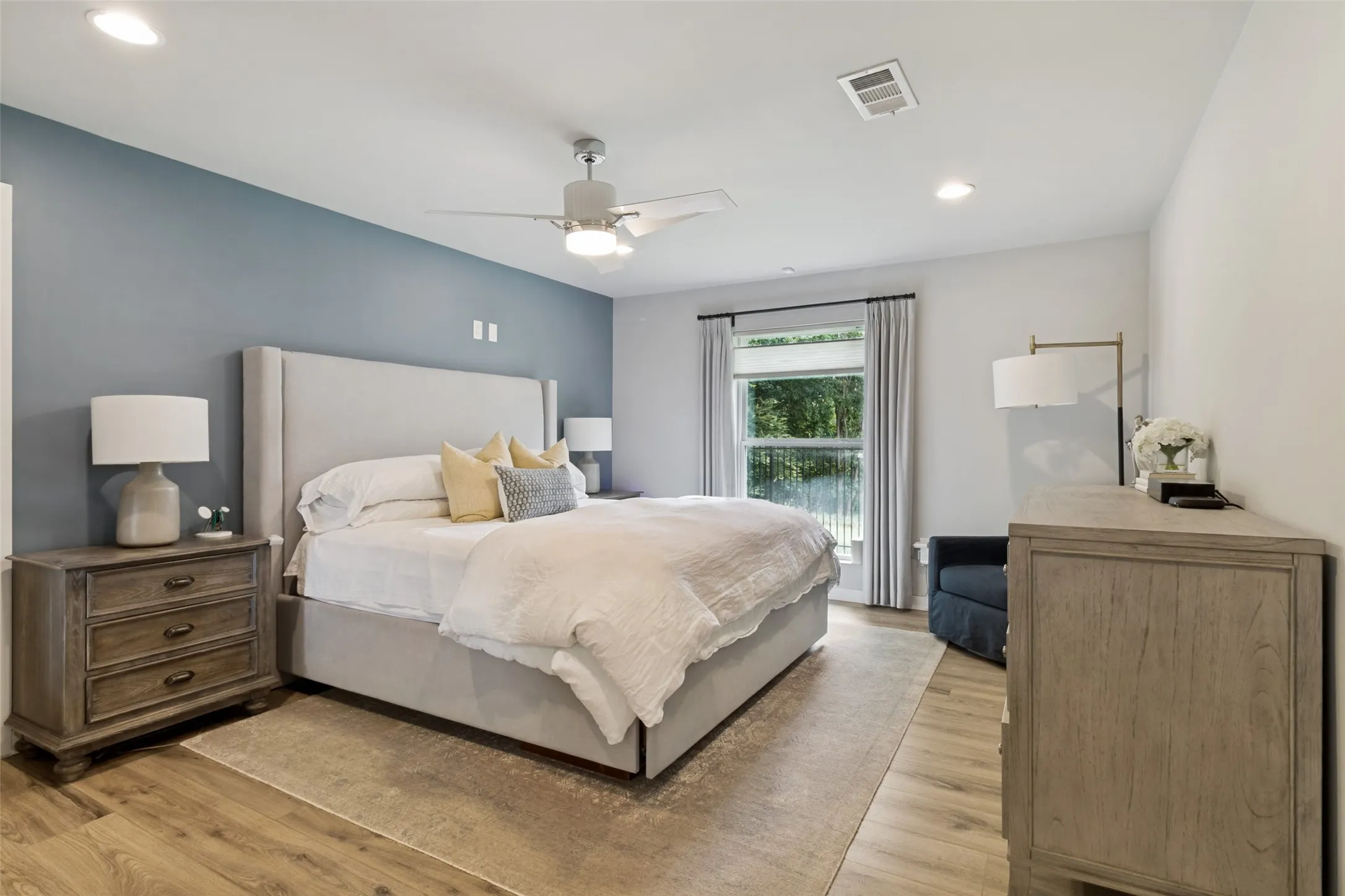 Spacious primary bedroom features the luxury vinyl plank flooring, custom blinds, and a calming designer color palette.