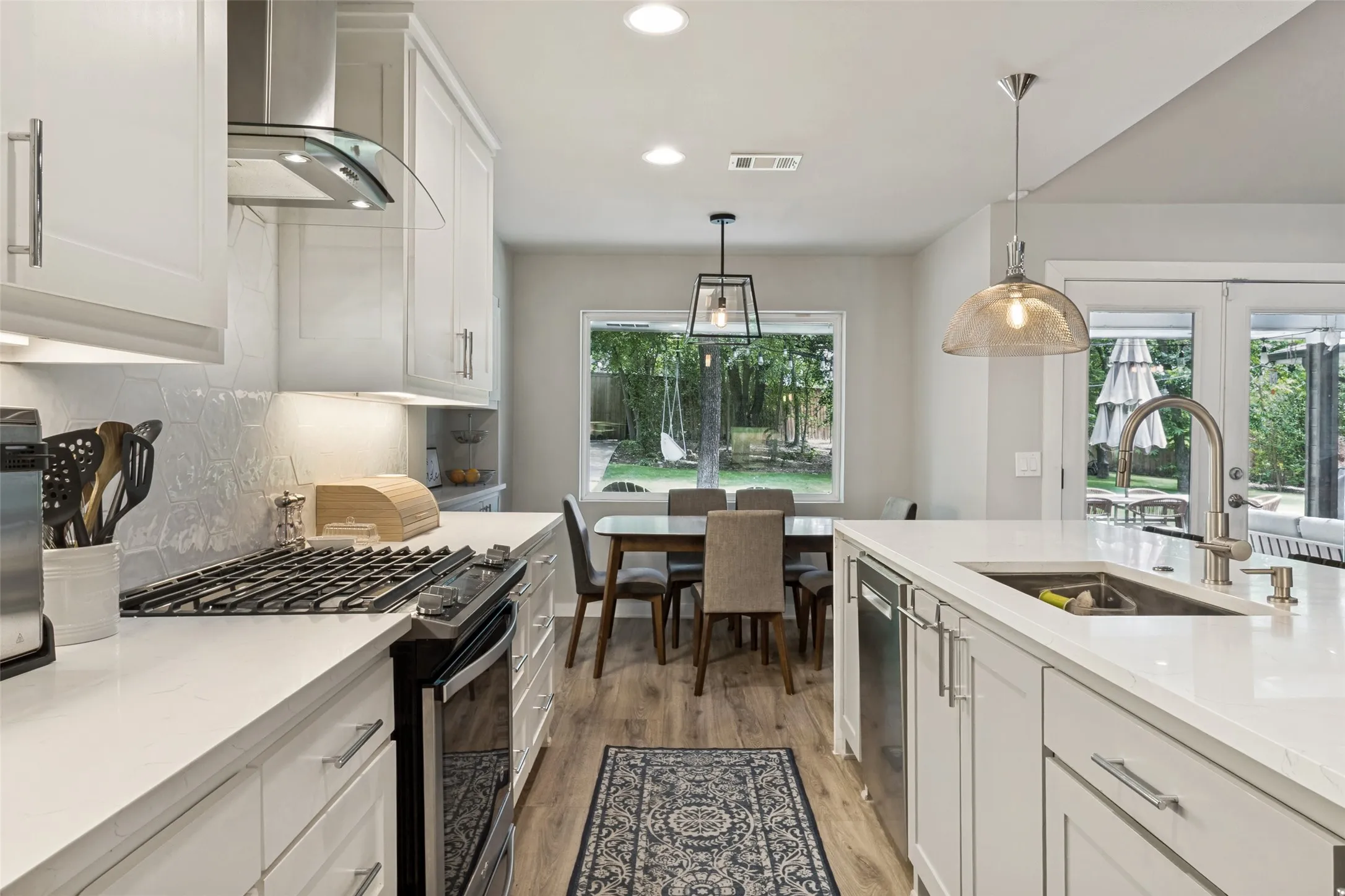 Bright and airy kitchen overlooks the backyard and features stainless steel appliances, quartz countertops, and extensive cabinet storage.