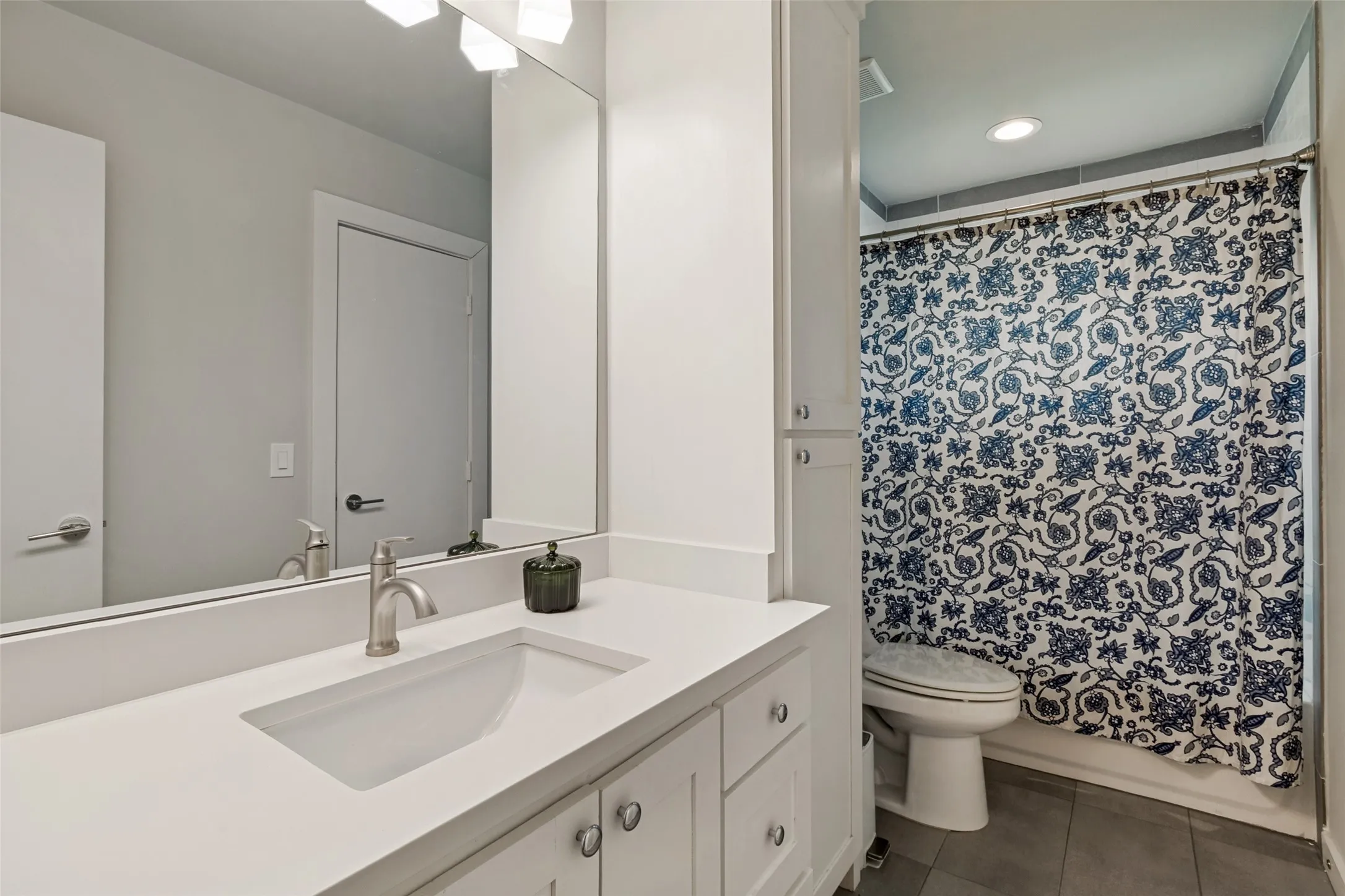Updated secondary bathroom features quartz countertops, modern fixtures, and a designer tile tub-shower surround.