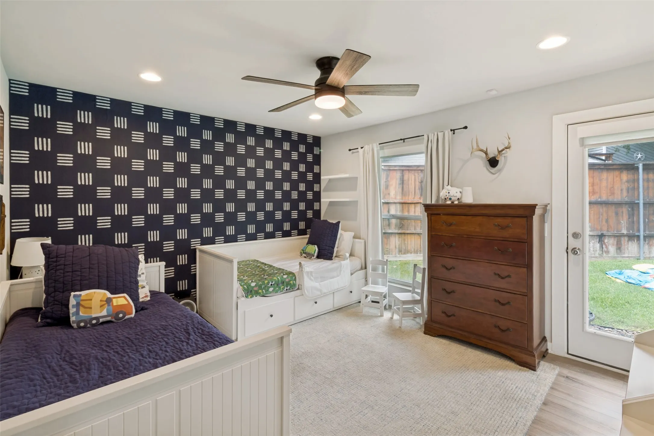 Generously sized secondary bedroom features designer wallpaper accent wall, abundant natural light, and its own private entrance—perfect for a guest suite.