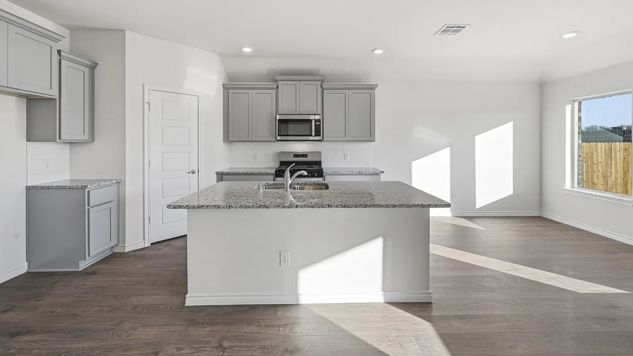 Open-concept kitchen featuring an island with an integrated sink, light gray cabinetry, granite countertops, and wood-finish flooring