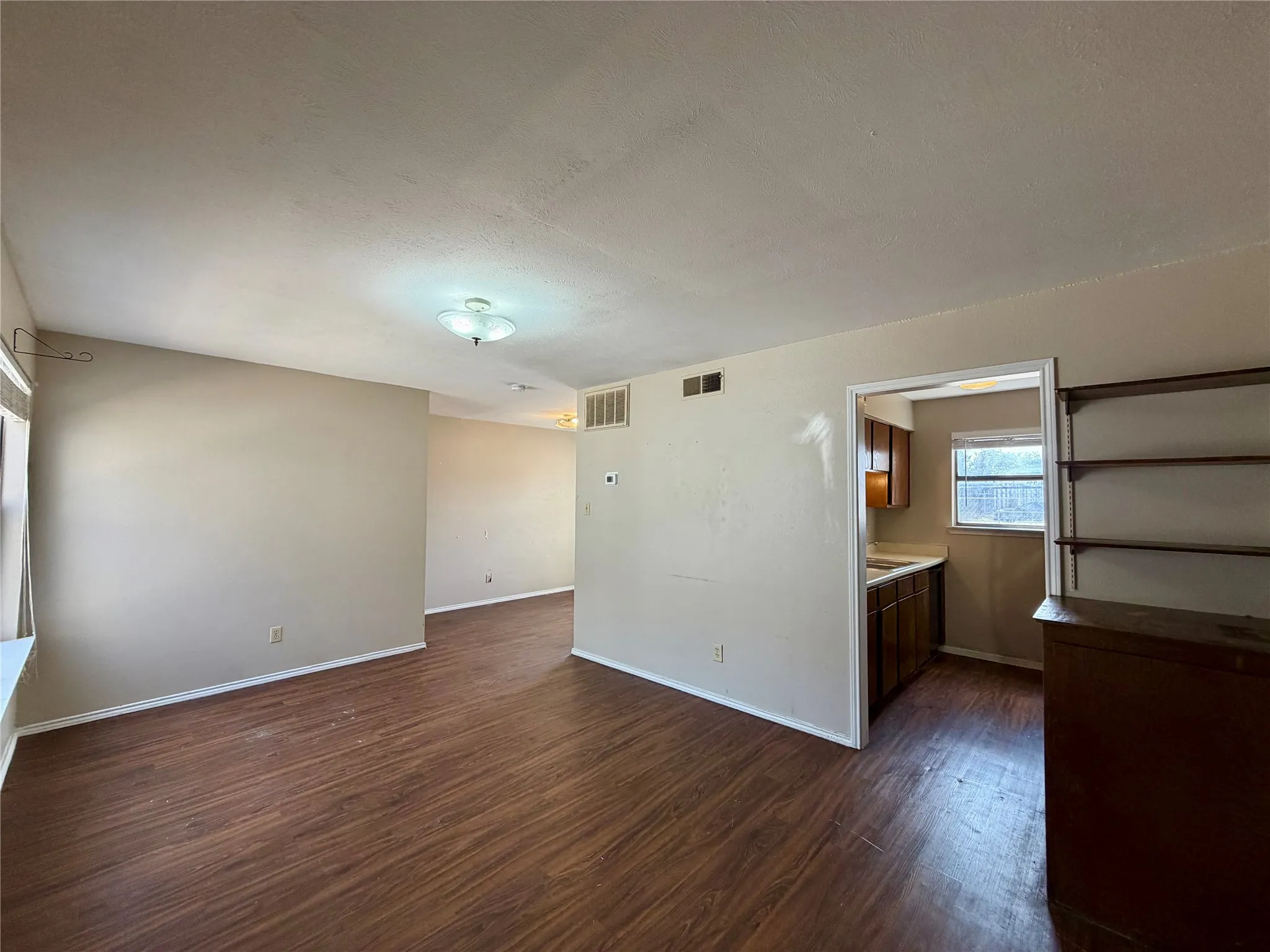 Wood-finish flooring throughout, neutral paint, flush mount lighting, and a defined kitchen alcove