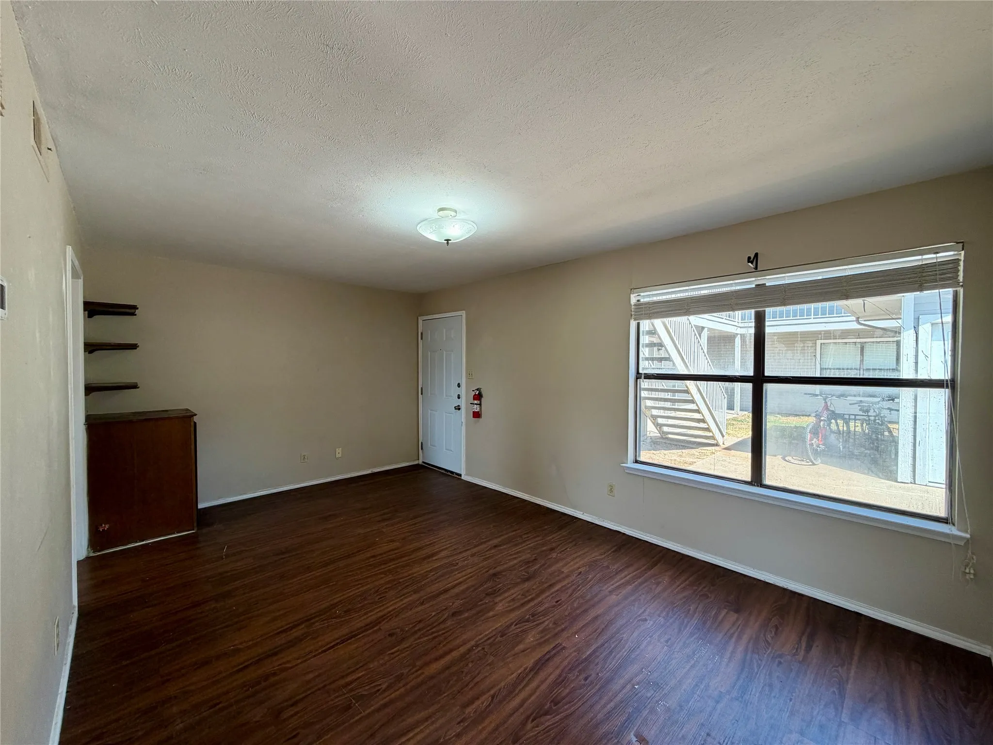 Wood-finish flooring, built-in shelving, and a large window with blinds