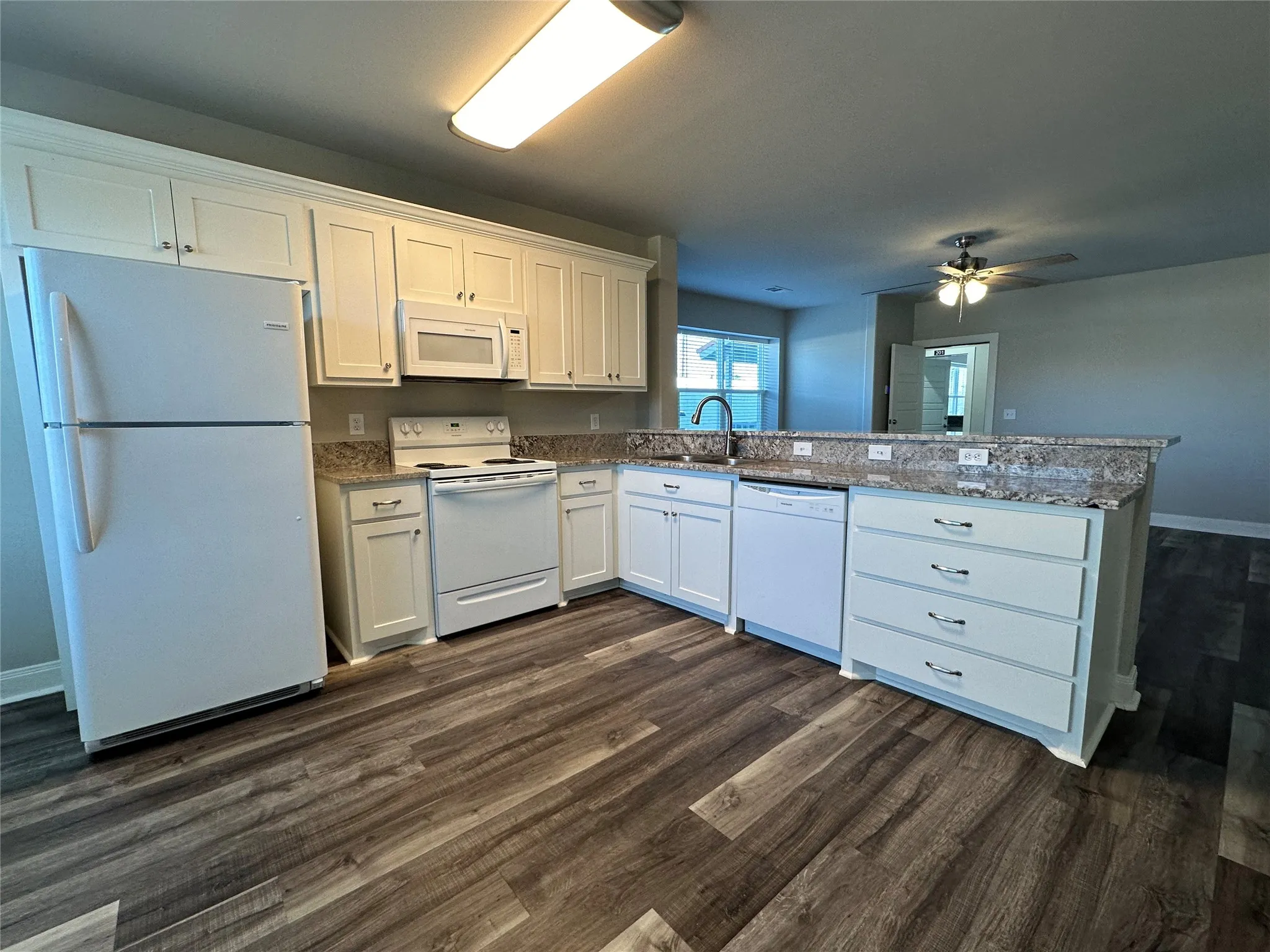 Kitchen featuring white cabinetry, granite countertops, wood-finish flooring, white appliances, and a breakfast bar