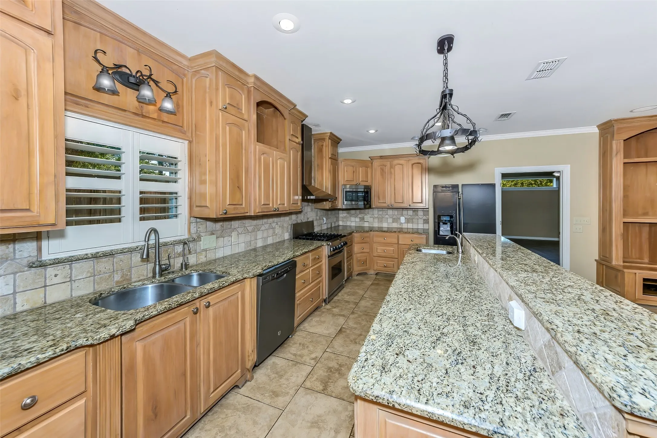 Kitchen featuring natural wood cabinetry, granite countertops, tile flooring, stainless steel appliances, and a breakfast bar