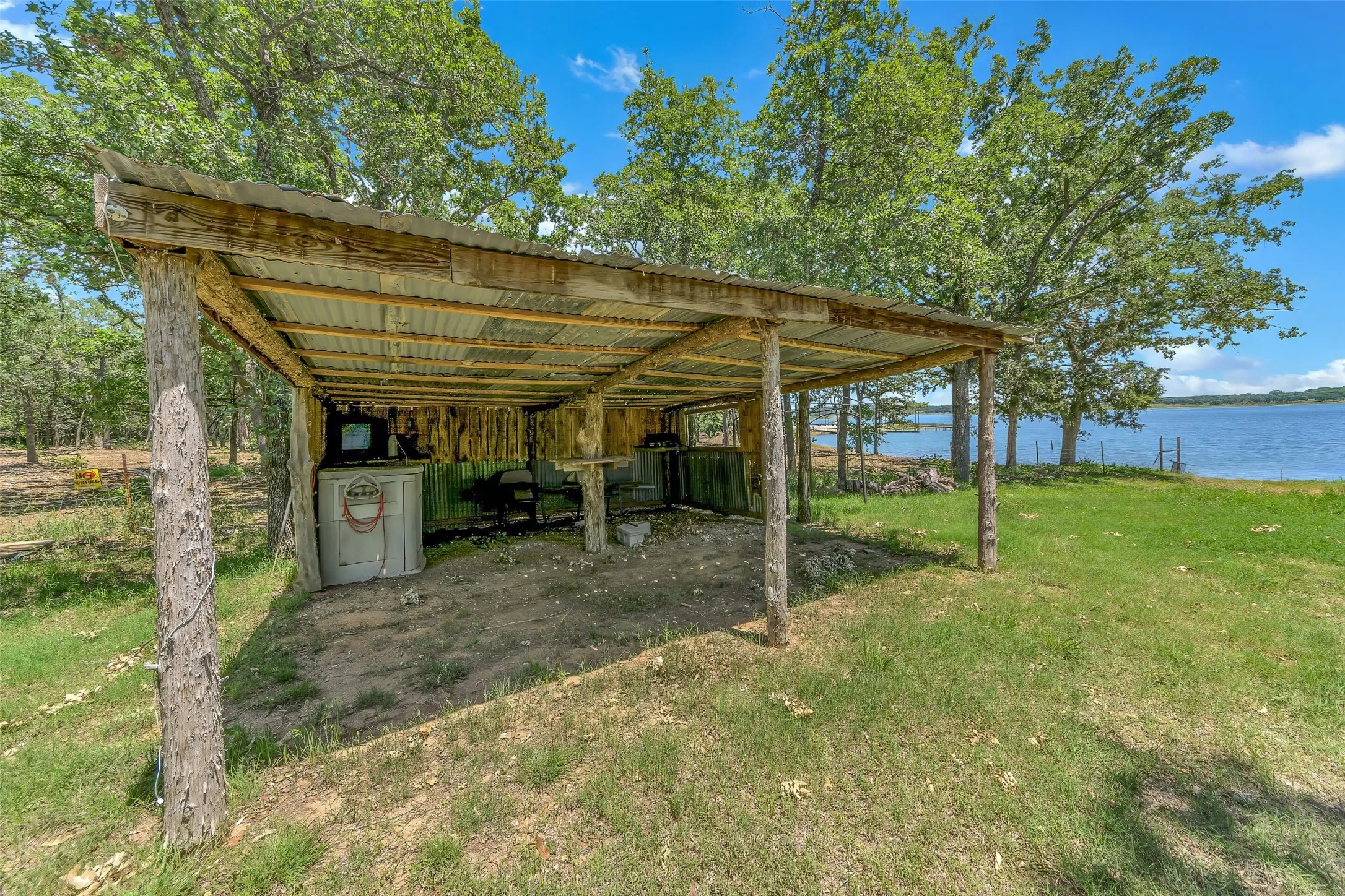 Rustic covered outdoor structure featuring natural wood posts and a corrugated metal roof