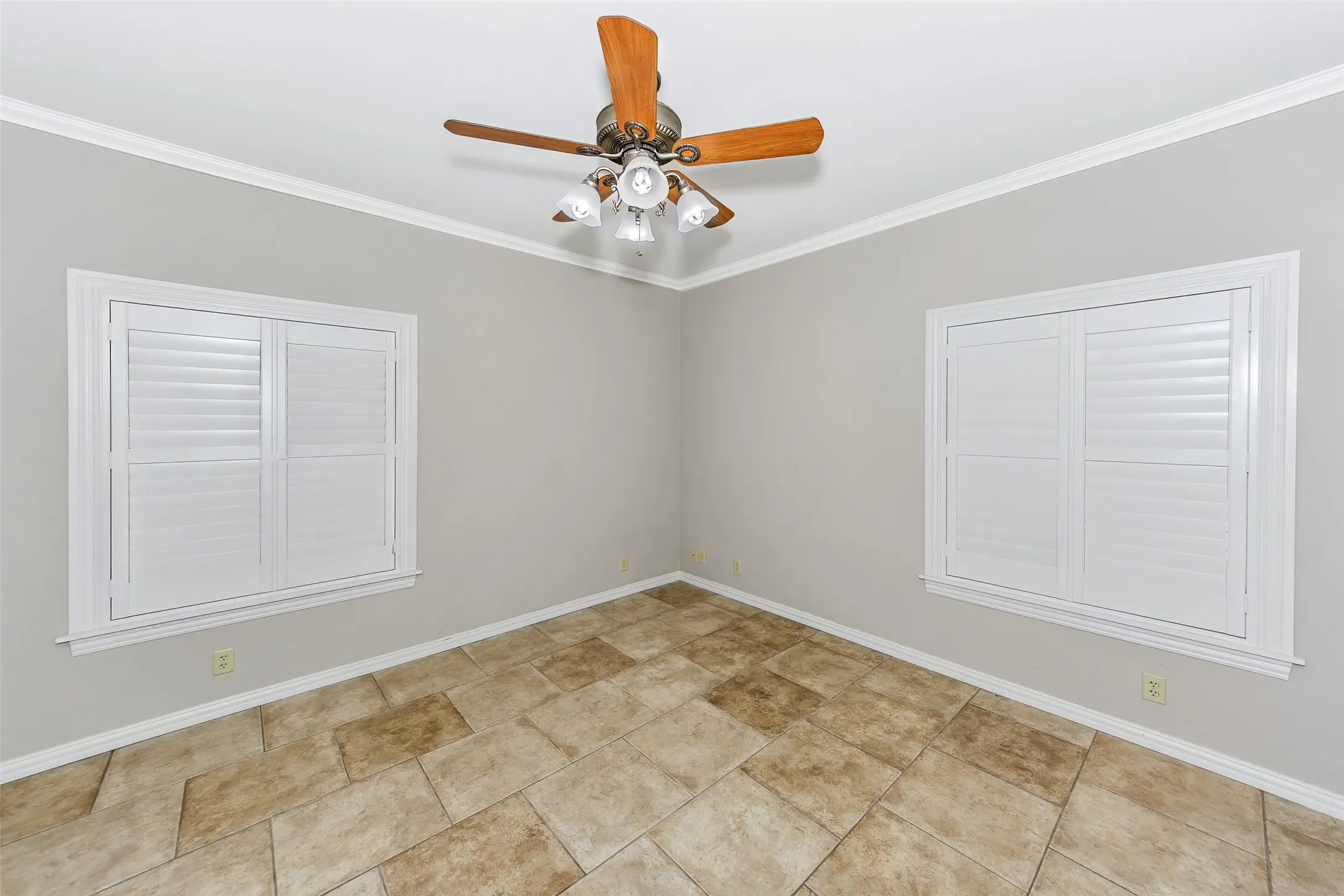 Room with light gray walls, crown molding, and large format tile flooring