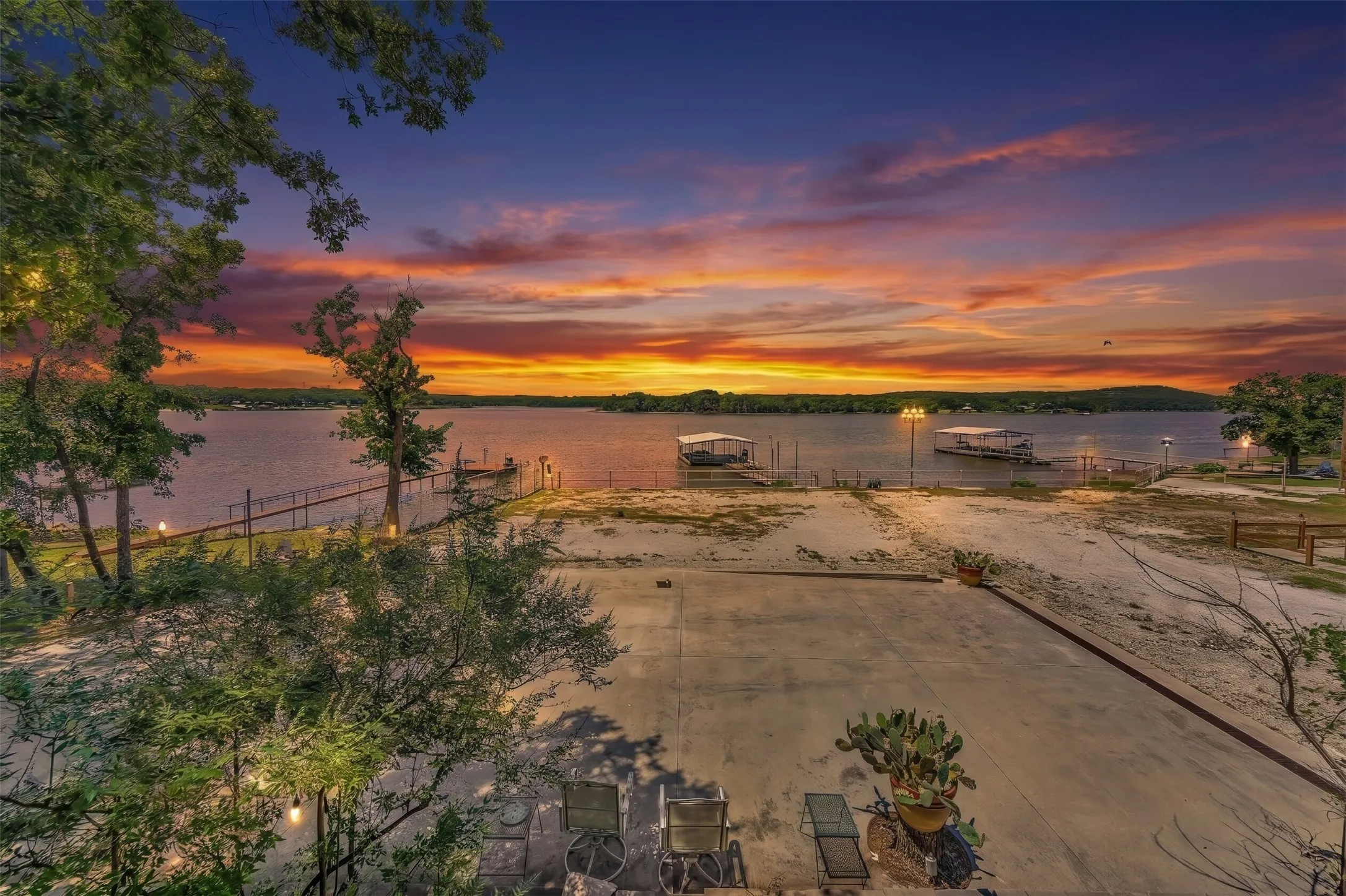 Waterfront property featuring multiple boat slips, a concrete patio, and mature trees
