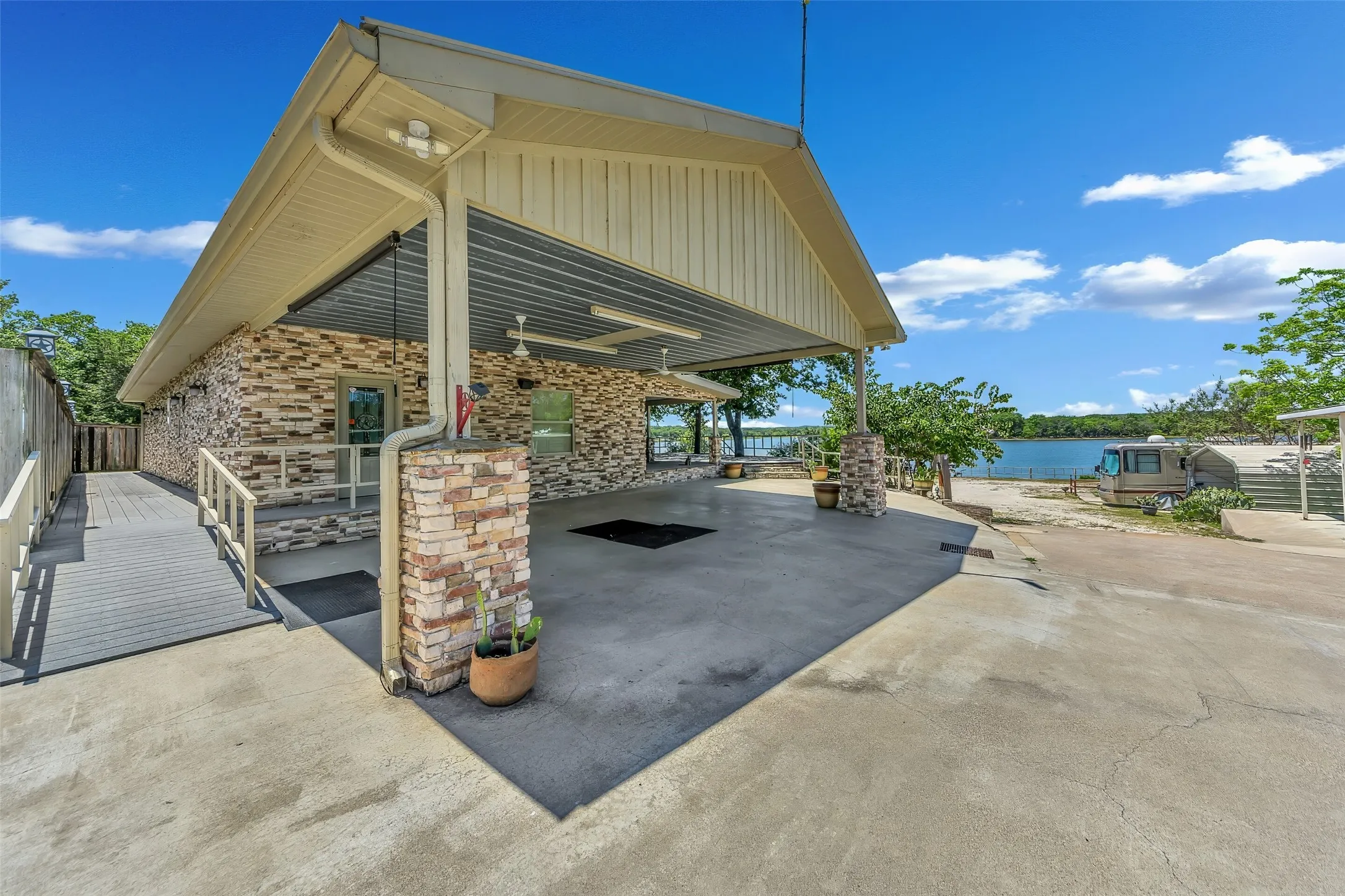 Exterior featuring stacked stone accents, covered outdoor area, concrete surfacing, and water frontage