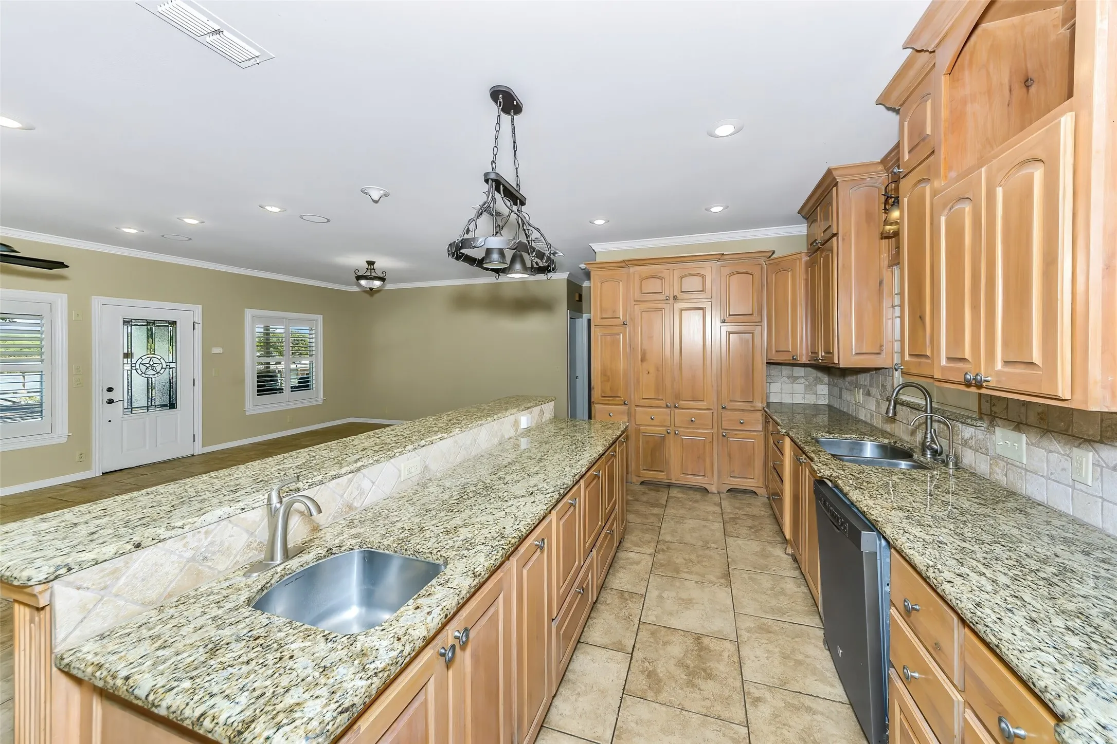 Kitchen featuring granite countertops, extensive wood cabinetry, tile flooring, and a double basin sink with a brushed nickel faucet