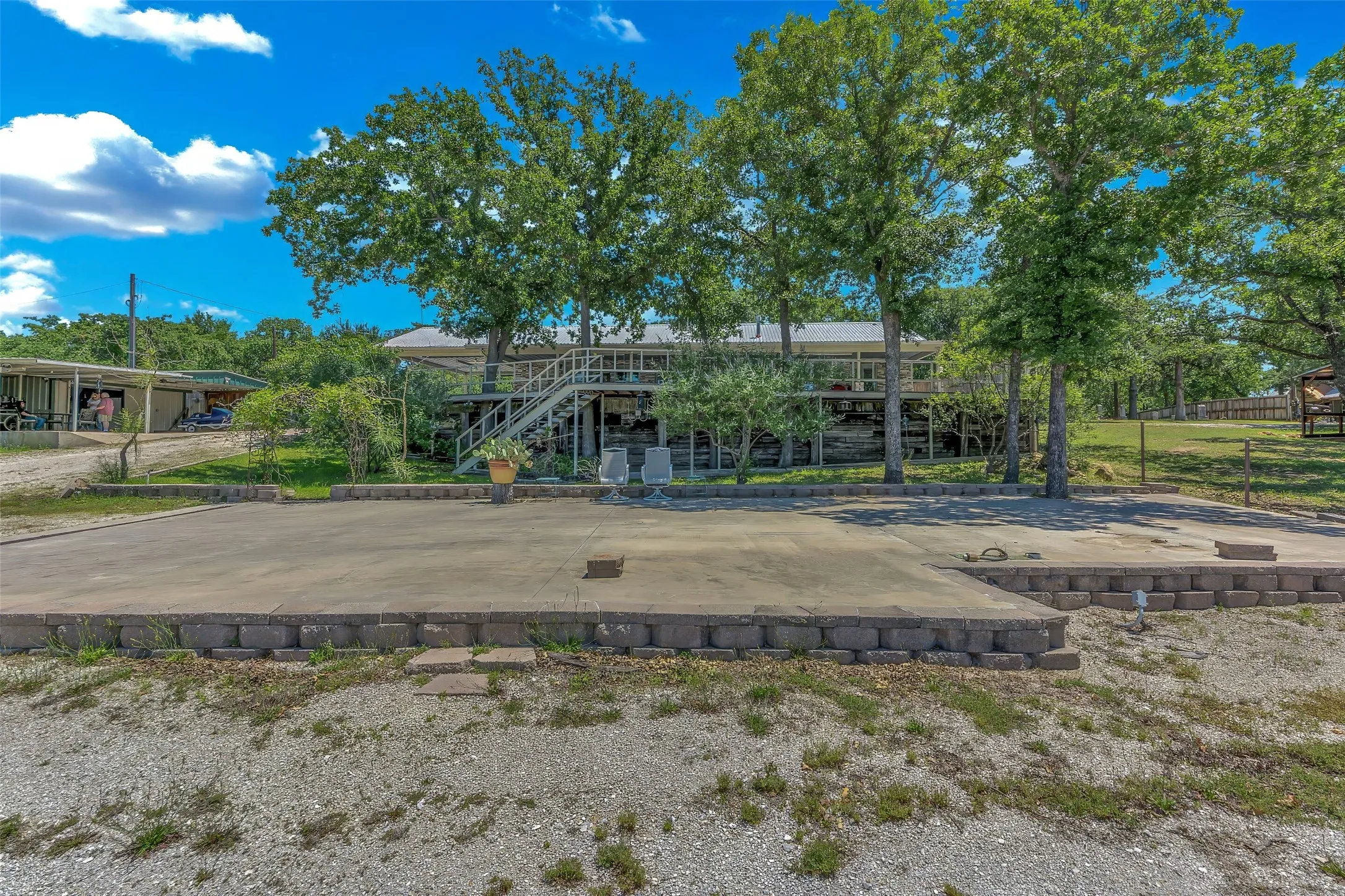 Expansive concrete pad bordered by a low block retaining wall, offering a tiered outdoor area