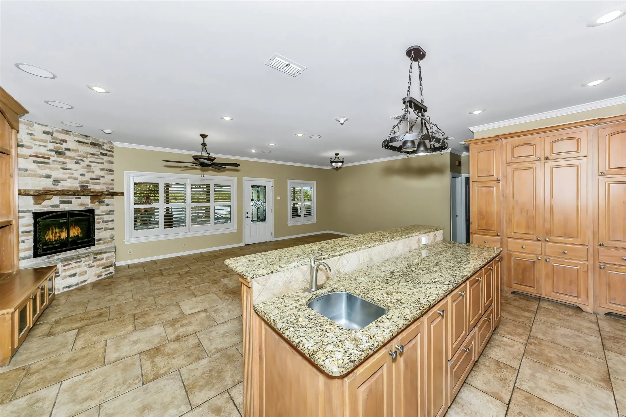 Spacious kitchen with wood cabinetry and light granite countertops, featuring a kitchen island with an undermount sink and a breakfast bar