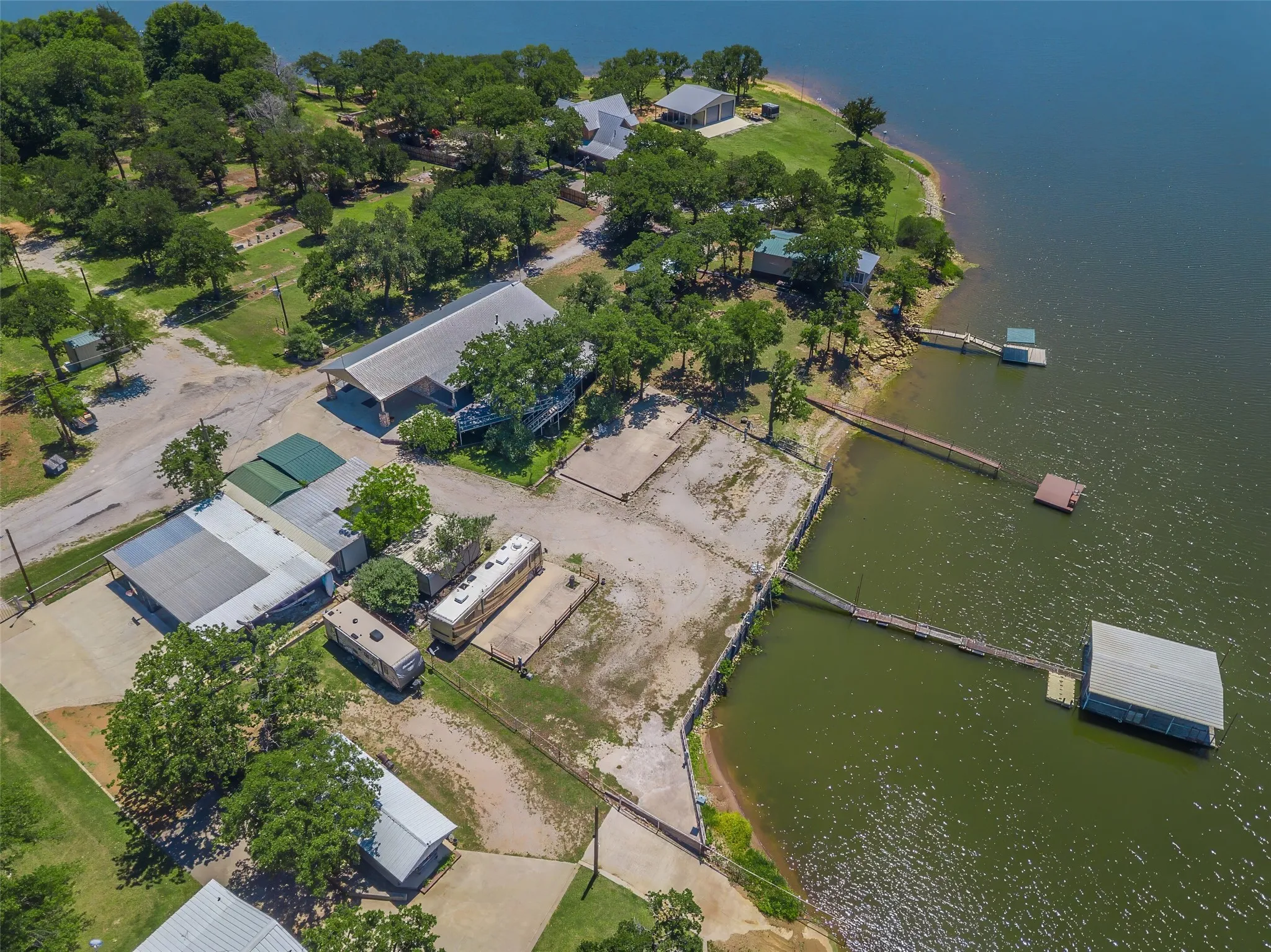 Waterfront property featuring multiple docks, a private boat house, and mature trees